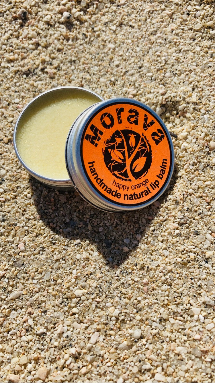 Natural lip balm in a 10 ml container with a happy orange scent, featuring organic ingredients like shea and cocoa butter.