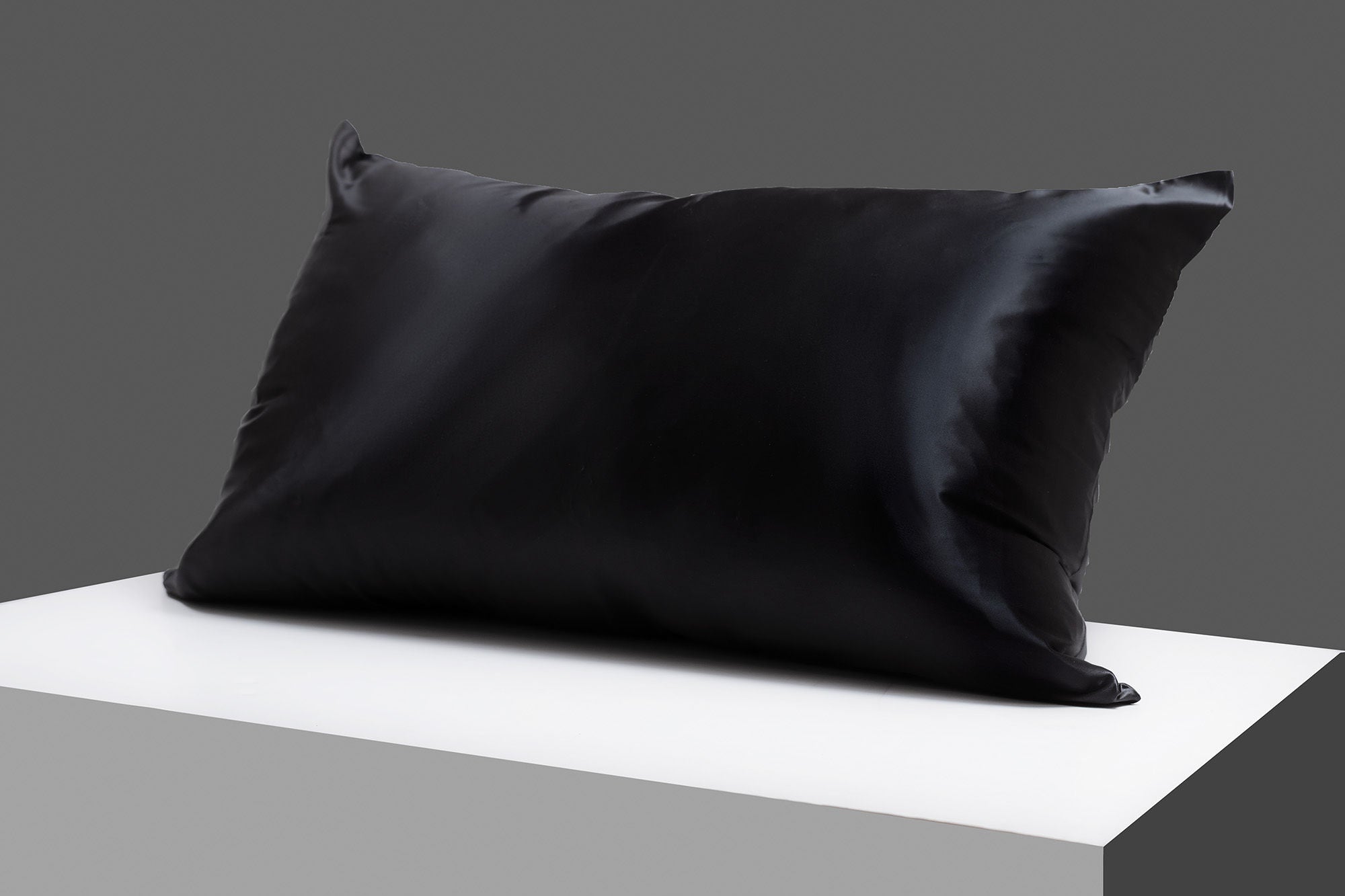 A pair of luxurious SIB™ silk pillowcases in elegant black and gold gift boxes, showcasing their soft texture and hidden zipper design.