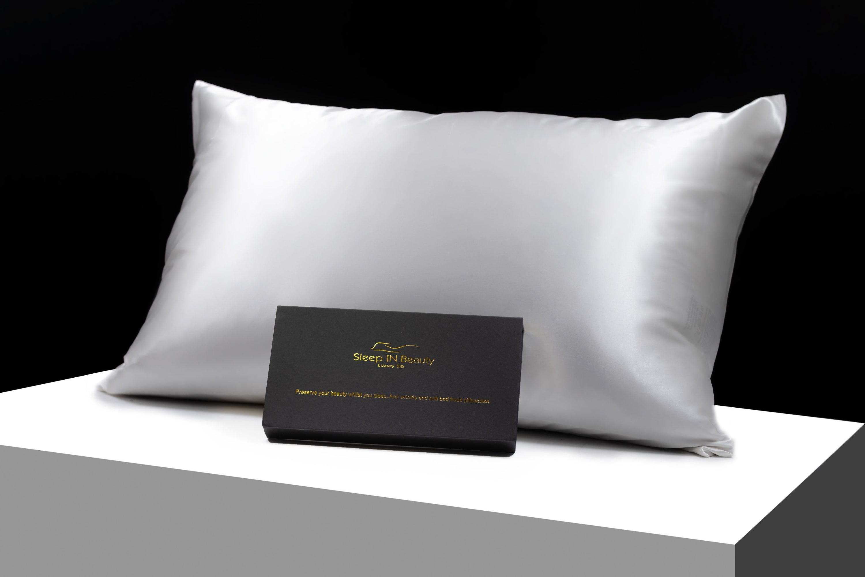 A pair of luxurious SIB™ silk pillowcases in elegant black and gold gift boxes, showcasing their soft texture and hidden zipper design.