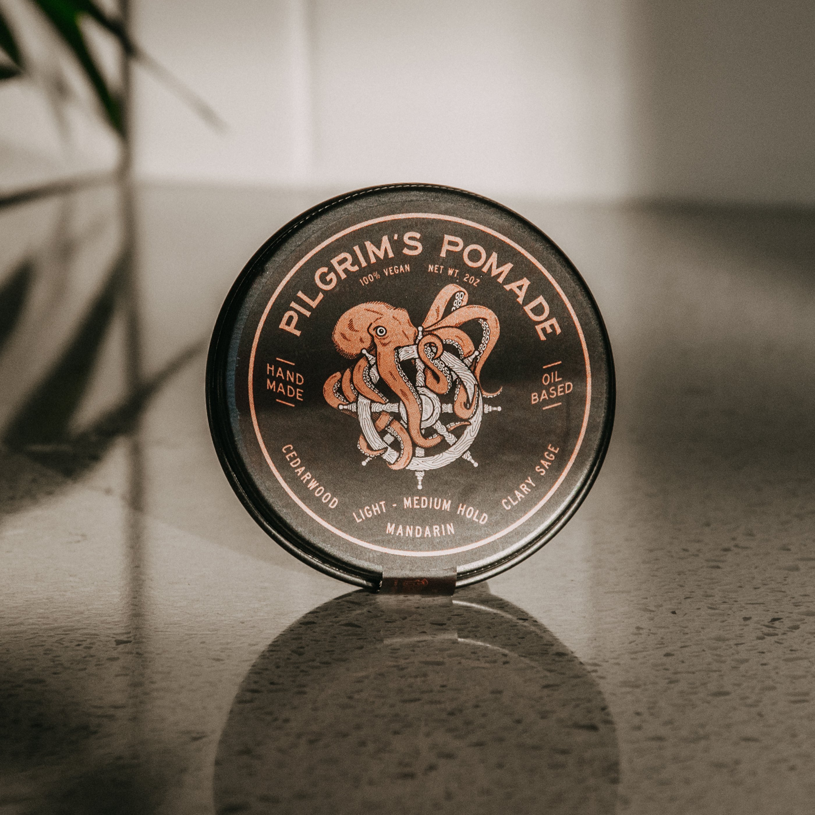 Pilgrim's® Vegan Pomade in a matte black travel tin, featuring a blend of mandarin and clary sage scents.