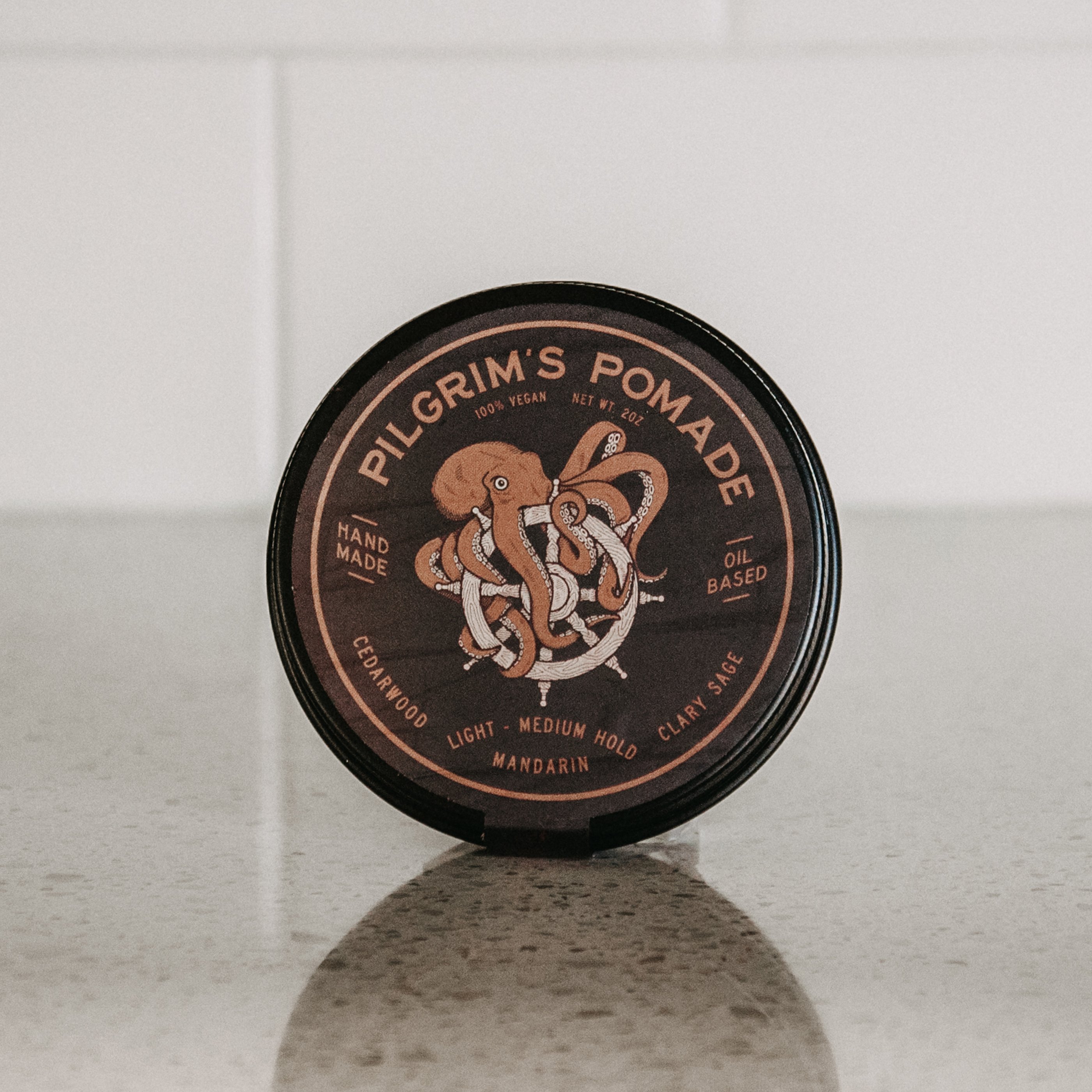 Pilgrim's® Vegan Pomade in a matte black travel tin, featuring a blend of mandarin and clary sage scents.