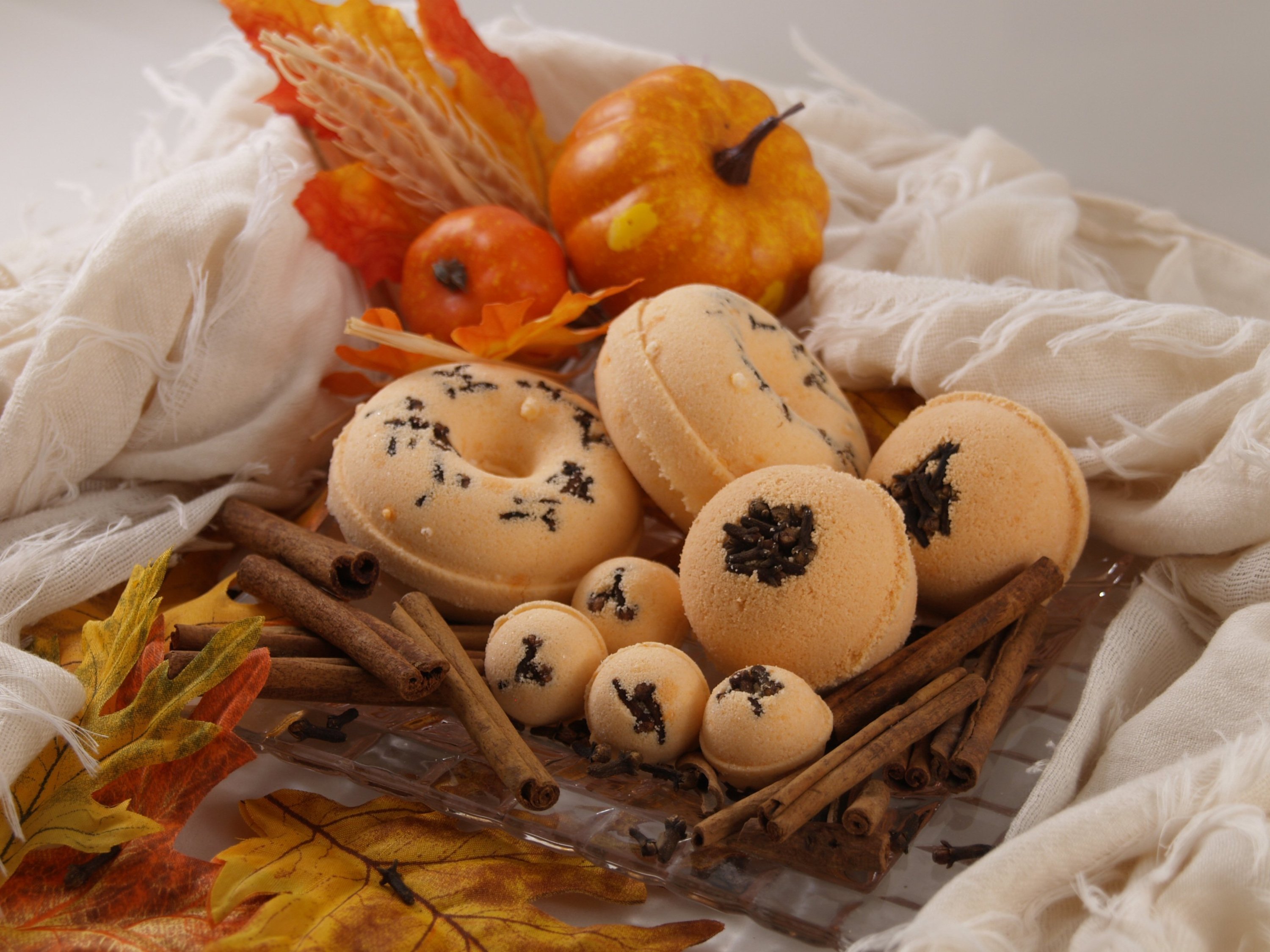 A vibrant Pumpkin Spice Bath Bomb with a decorative clove topping, showcasing its rich colors and inviting aroma.