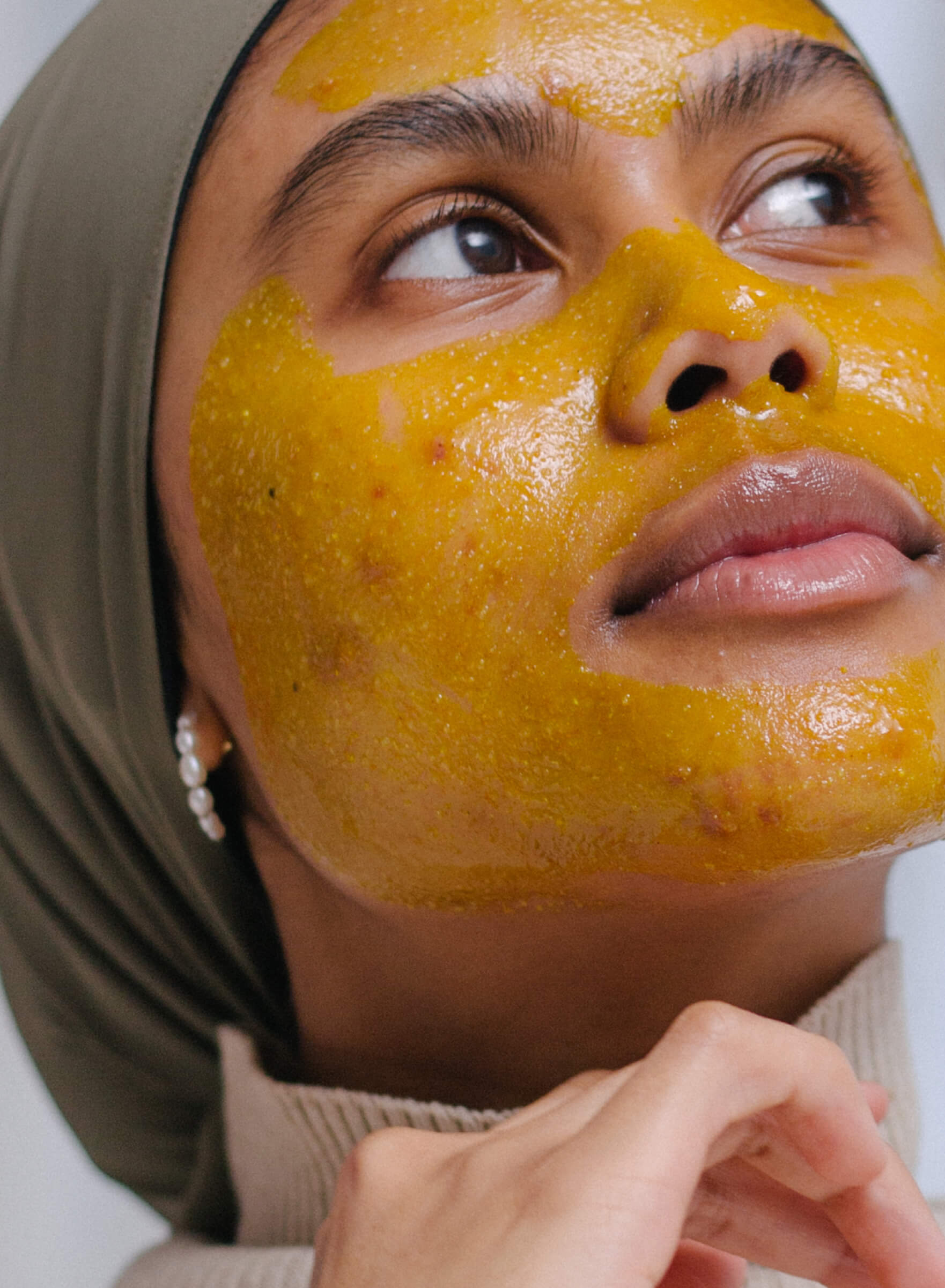 Red Erase Face Scrub in a jar with a wooden spoon, showcasing its natural ingredients like turmeric and chickpea flour.