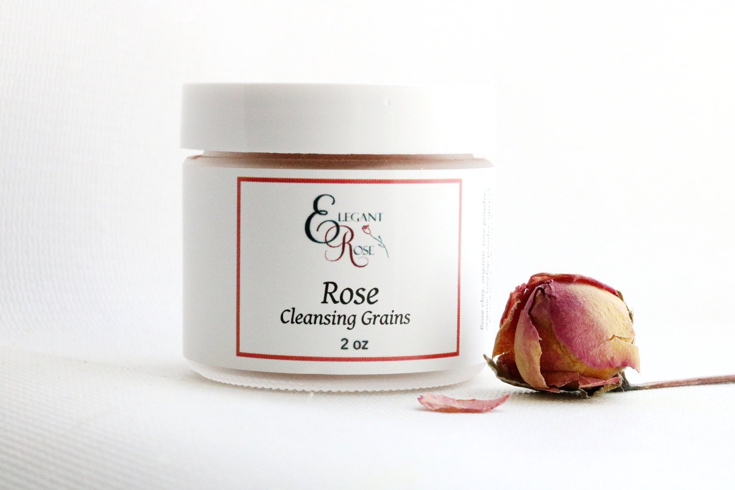 A 2-ounce glass jar of Rose Cleansing Grains, showcasing its natural ingredients and exfoliating properties.