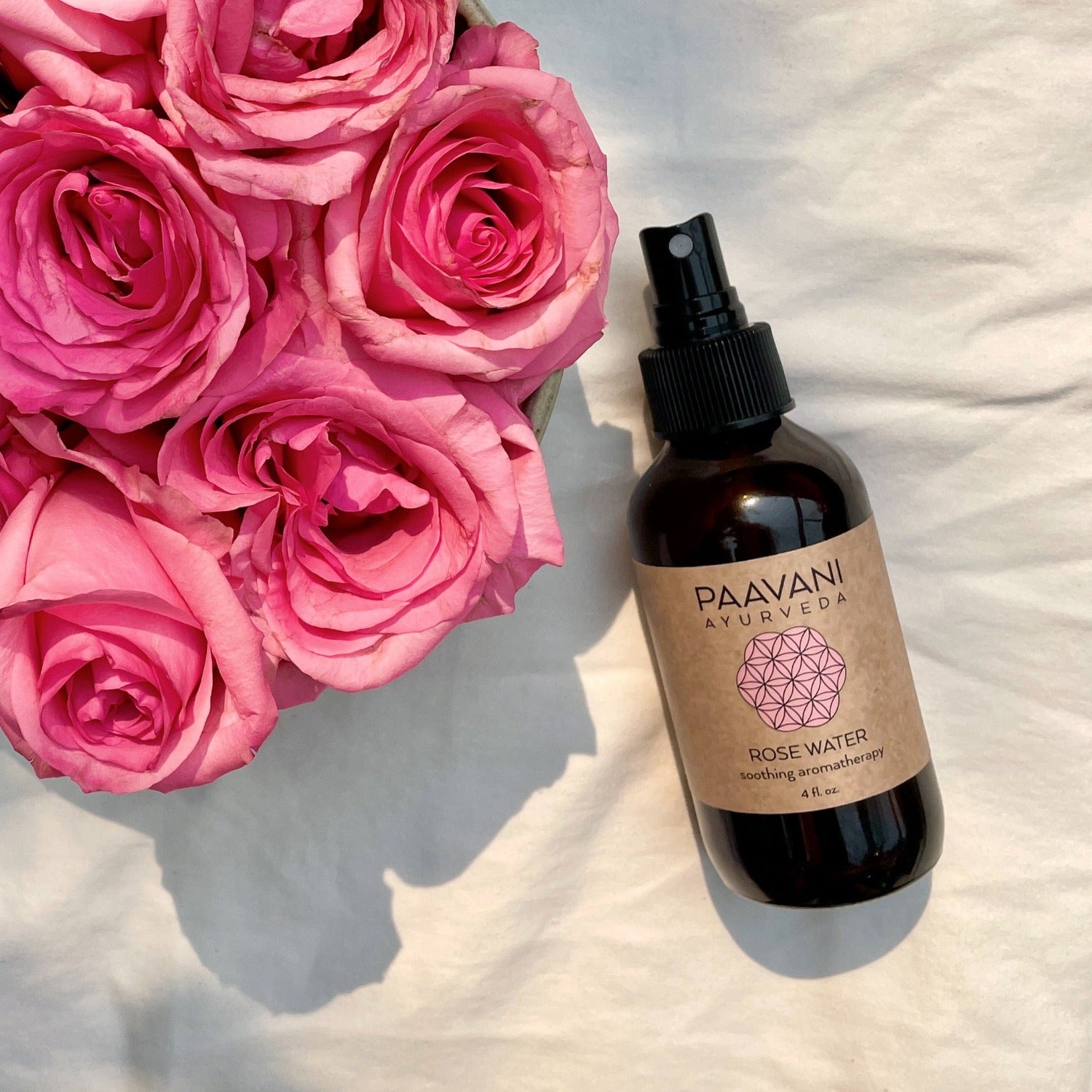 A bottle of organic Bulgarian rose water with a delicate floral design, surrounded by fresh roses.