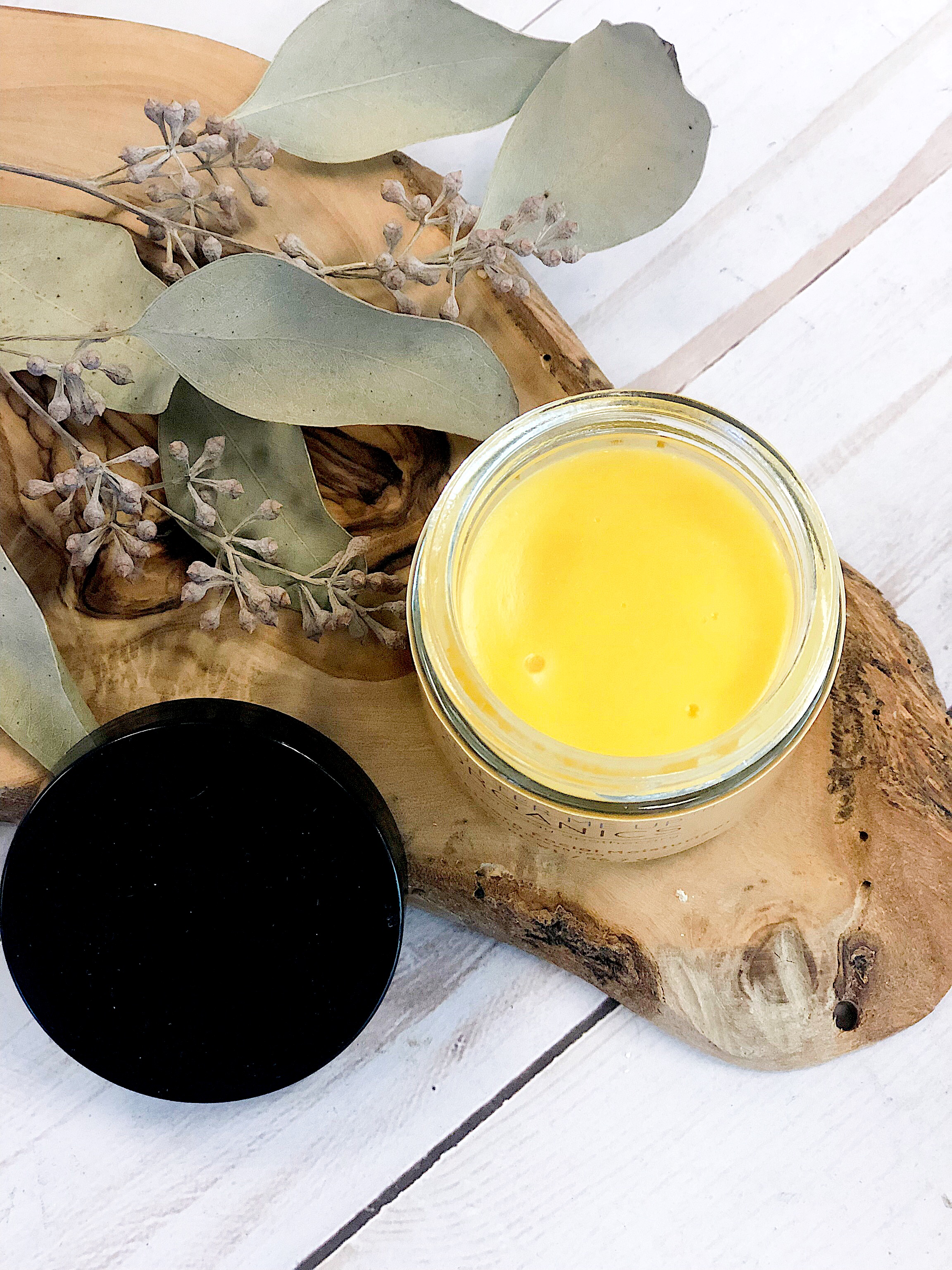 A 2-ounce glass jar of Sea Buckthorn Facial Moisturizer with a metal lid, showcasing its vibrant red color from organic sea buckthorn oil, surrounded by natural ingredients.