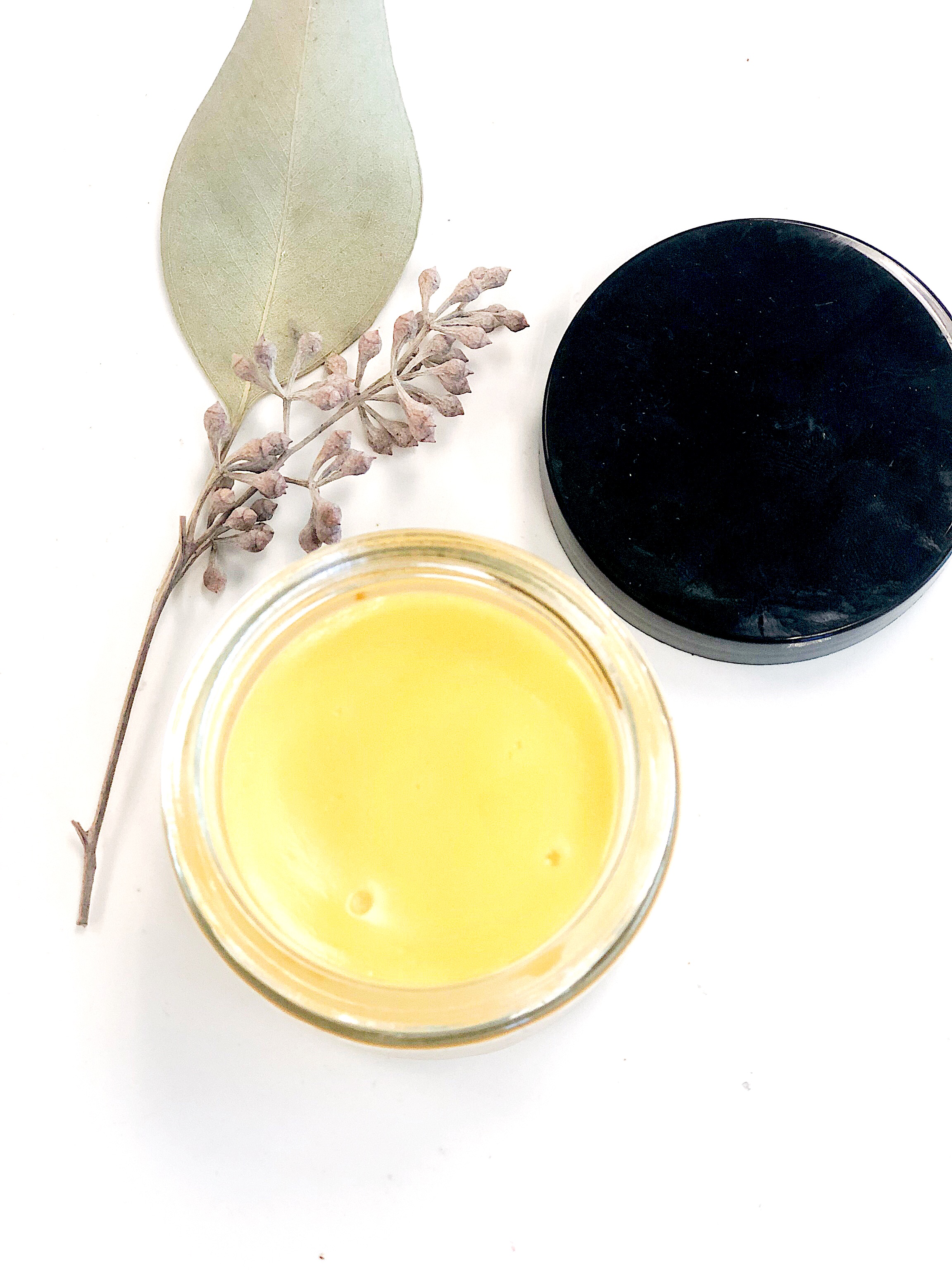 A 2-ounce glass jar of Sea Buckthorn Facial Moisturizer with a metal lid, showcasing its vibrant red color from organic sea buckthorn oil, surrounded by natural ingredients.