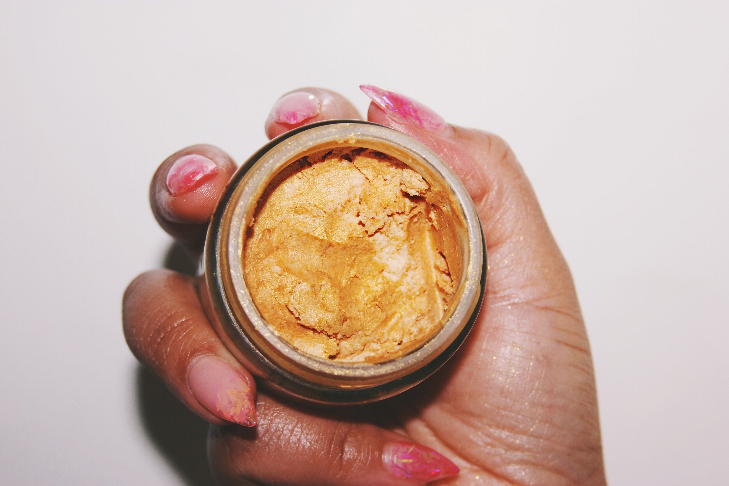 A jar of Shim Shimmer Body Butter showcasing its creamy texture and golden shimmer, surrounded by natural ingredients like shea butter and essential oils.