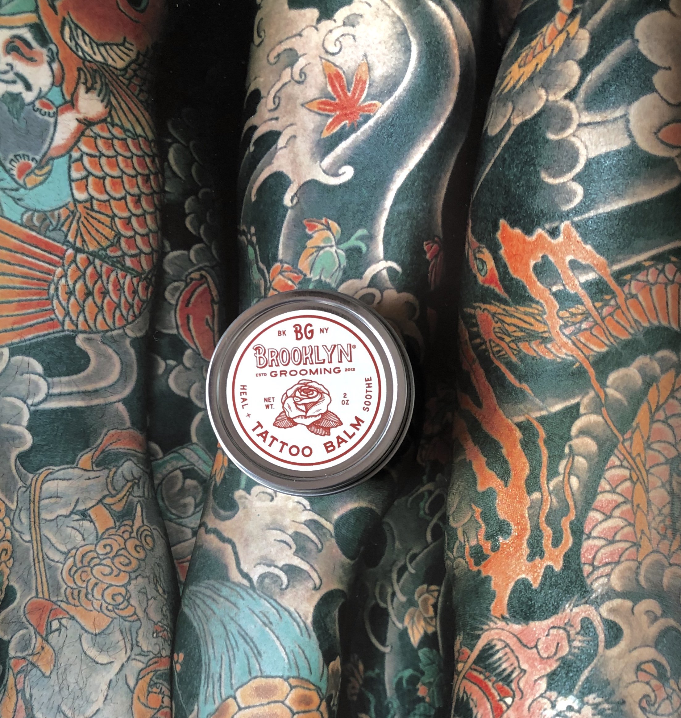 A 2 oz. jar of Tattoo Balm featuring natural ingredients for tattoo aftercare, with a soothing texture and organic label.