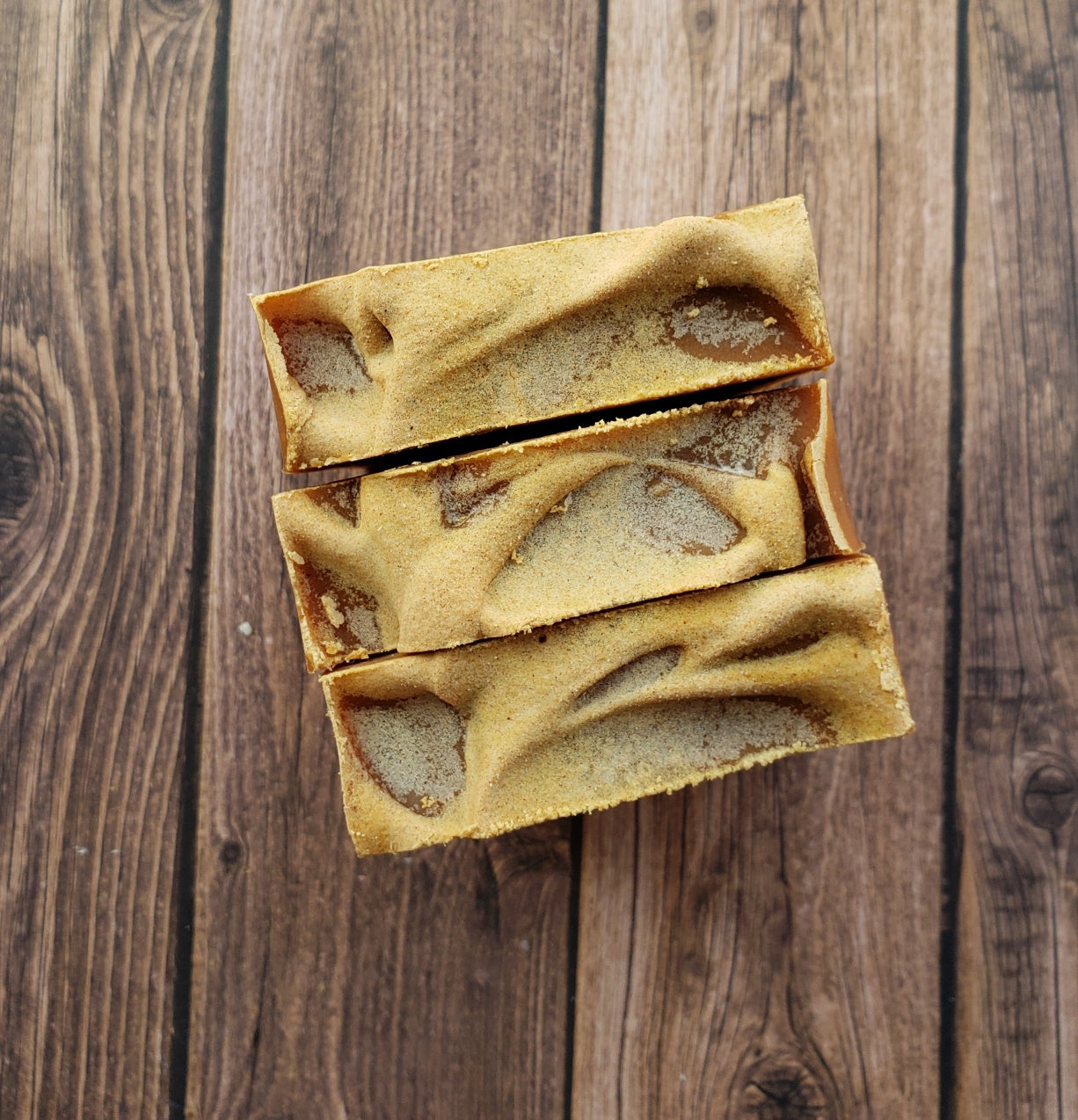 Turmeric Handmade Soap bar with a vibrant yellow color, showcasing its unique texture and natural ingredients, placed on a wooden surface.