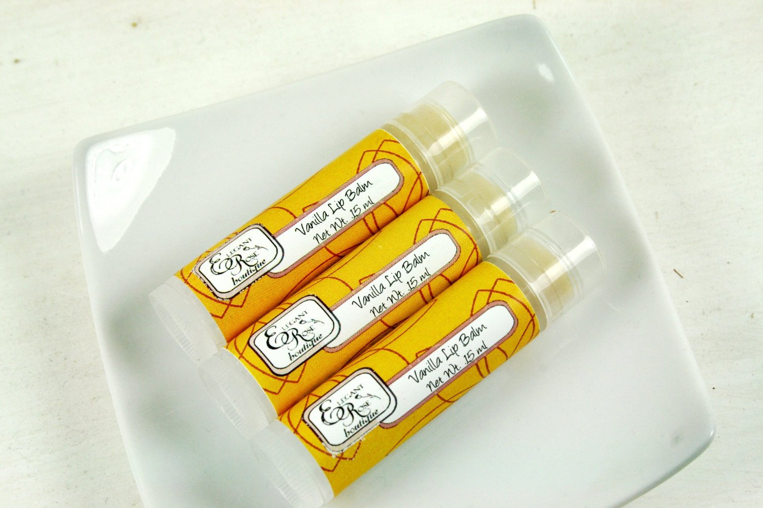 A tube of Vanilla Lip Balm with a creamy texture, featuring a label with vanilla flowers and organic ingredients.