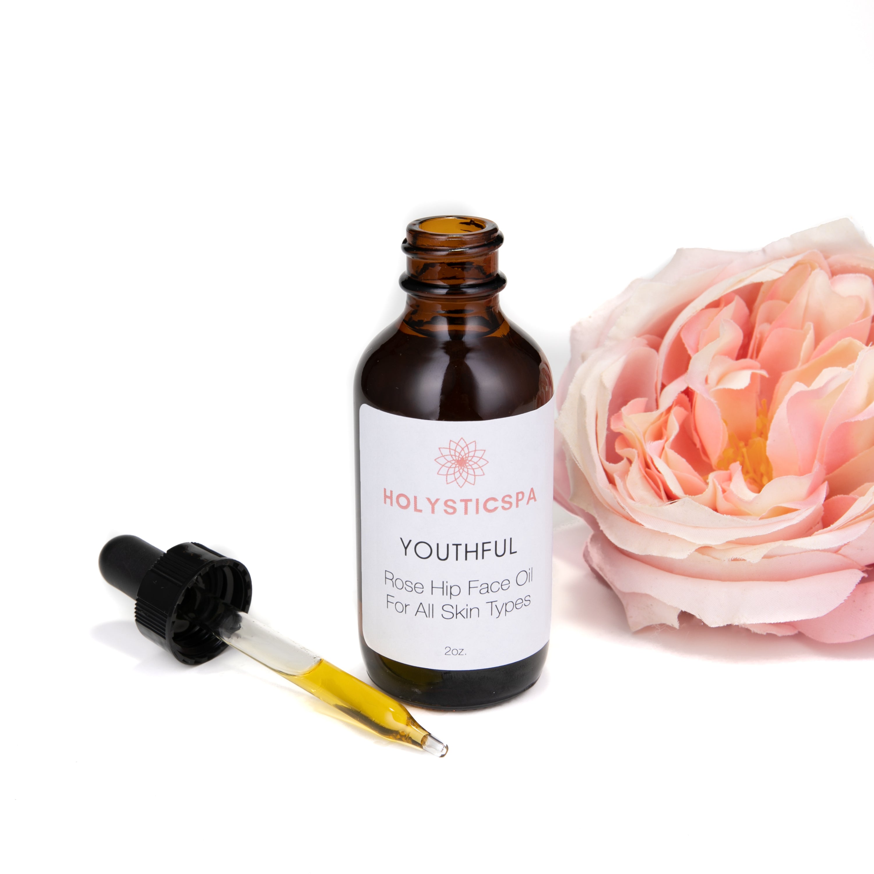 A bottle of Youthful Rosehip Face Oil with a dropper, surrounded by natural ingredients like rose hips and essential oils, showcasing its organic formulation.