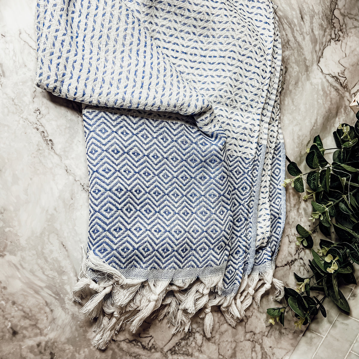 Azra Towel 200GSM in blue and gray with decorative tassels, showcasing its oversized design and soft texture.