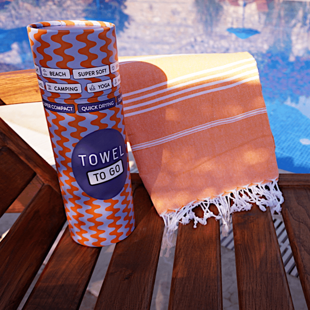 Ipanema Hammam Towel in vibrant orange with white stripes, elegantly displayed in a recycled gift box.