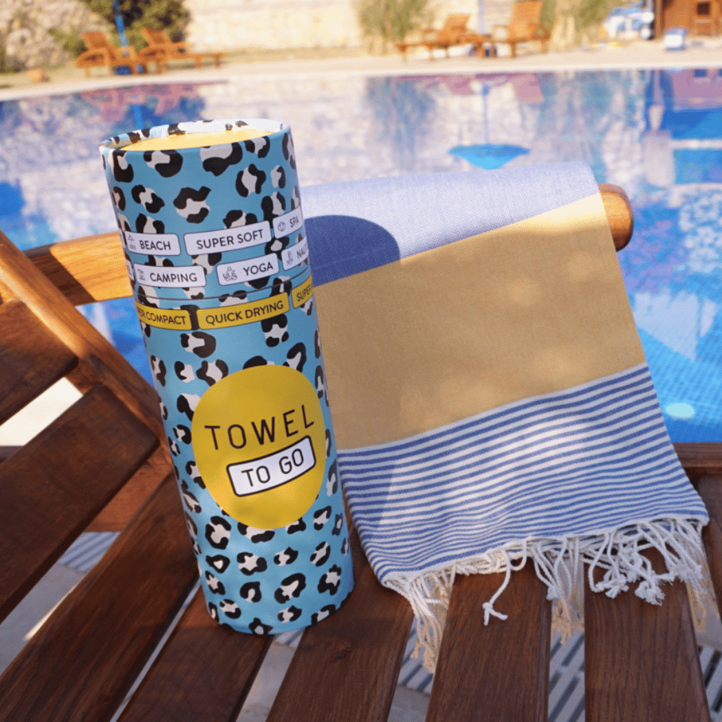 Palermo Beach Towel featuring vibrant blue and yellow stripes, handwoven from 100% cotton, displayed in a recycled gift box.