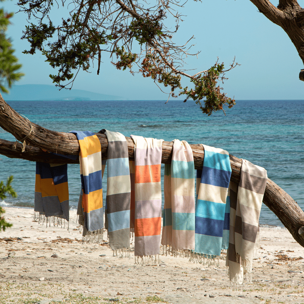 Palermo Beach Towel featuring vibrant blue and yellow stripes, handwoven from 100% cotton, displayed in a recycled gift box.