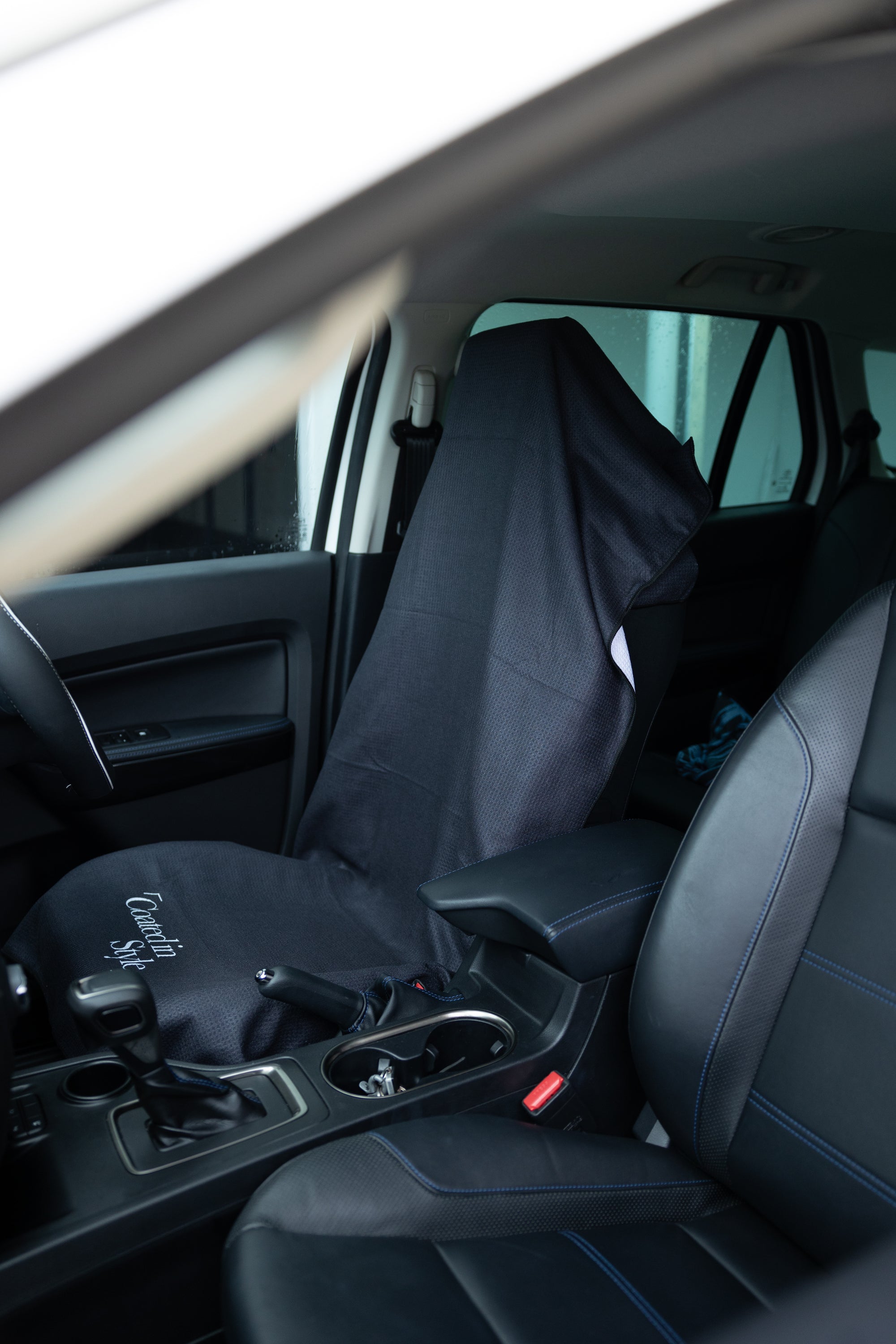 THE OG TOWEL in sleek black color, designed for car seats and beach use, showcasing its hooded shape and microfiber material.