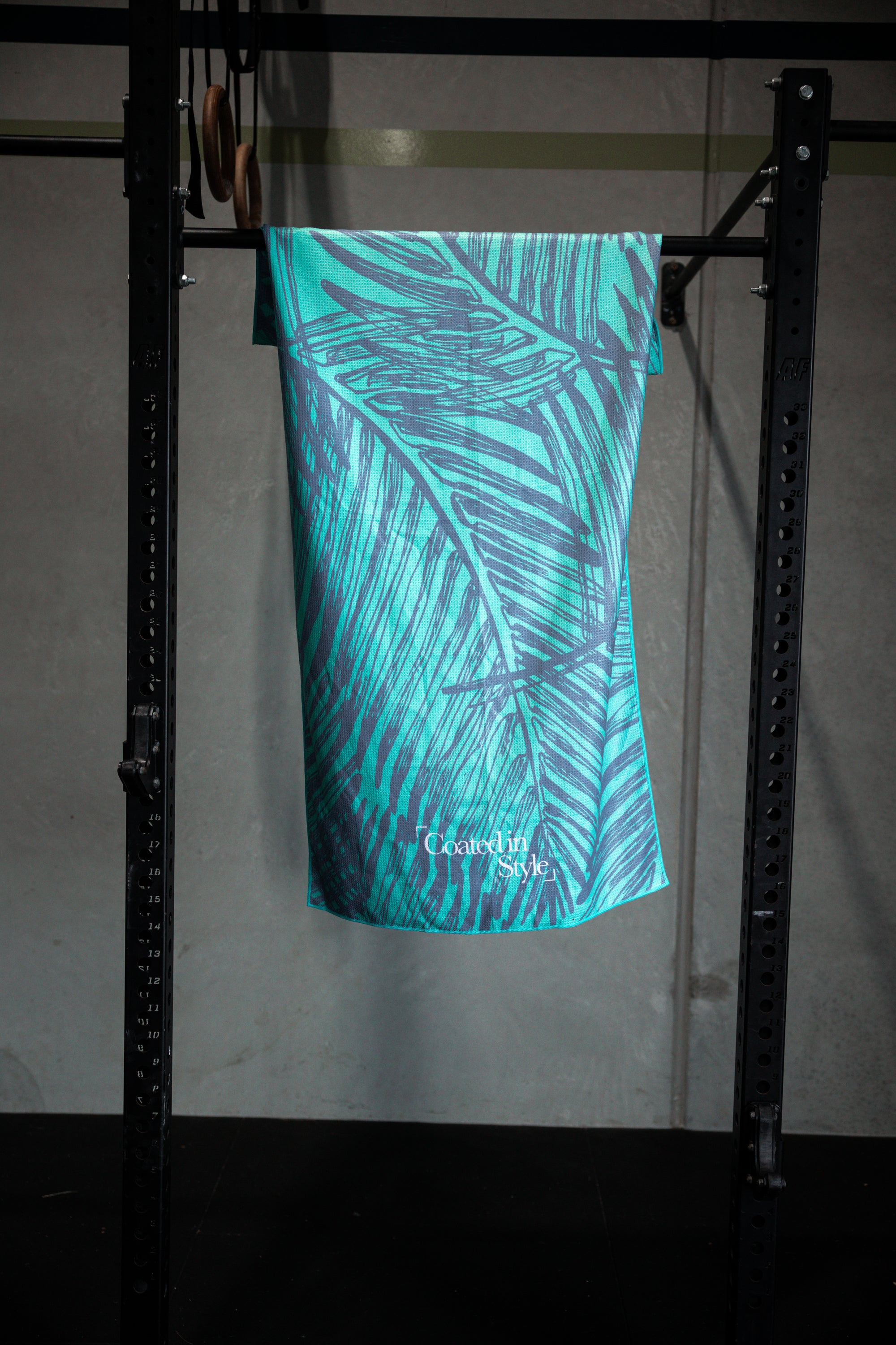 The Rainforest Aqua towel featuring a vibrant rainforest design in three colors, showcasing its microfibre texture and functional shape.