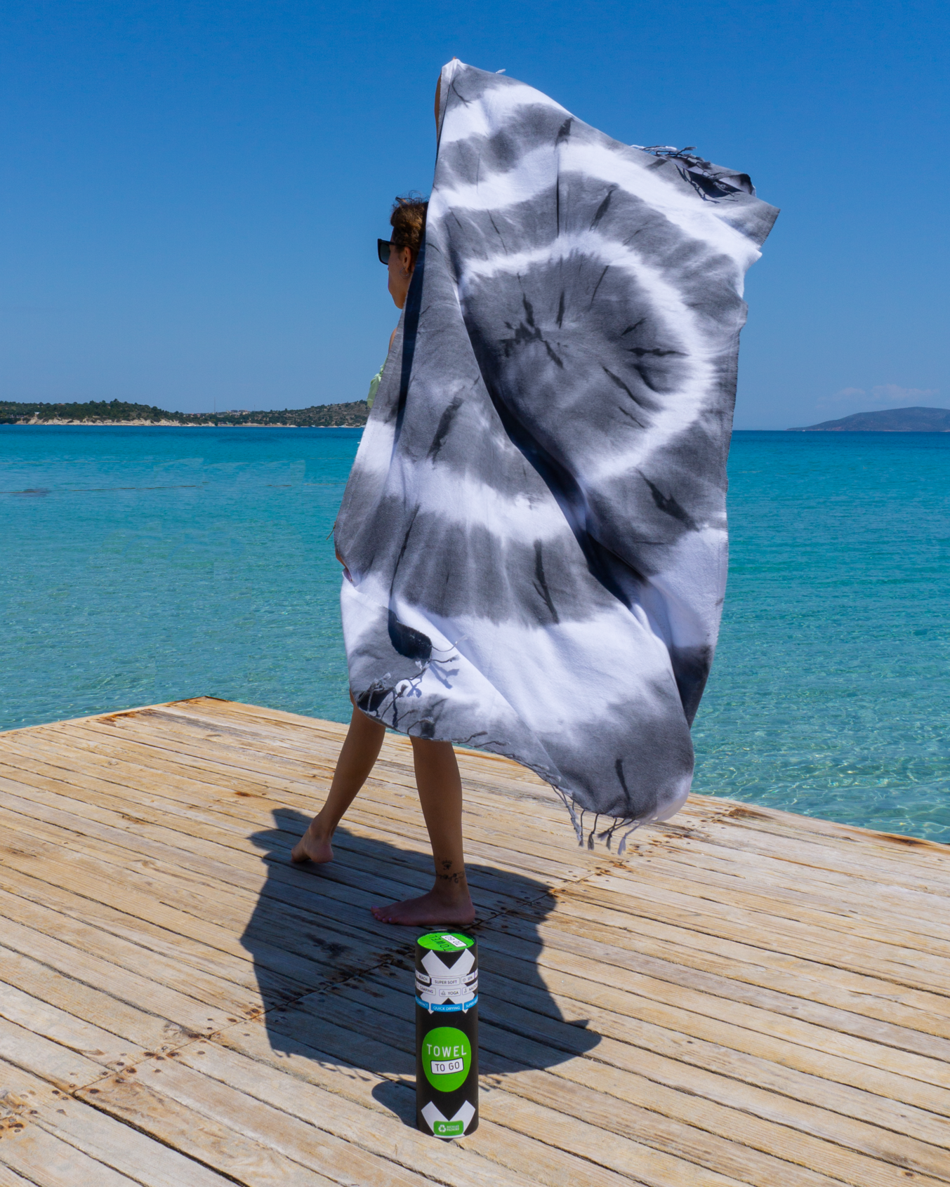 A vibrant tie-dye beach towel in black and white, elegantly displayed in a recycled gift box, showcasing its unique patterns and eco-friendly design.