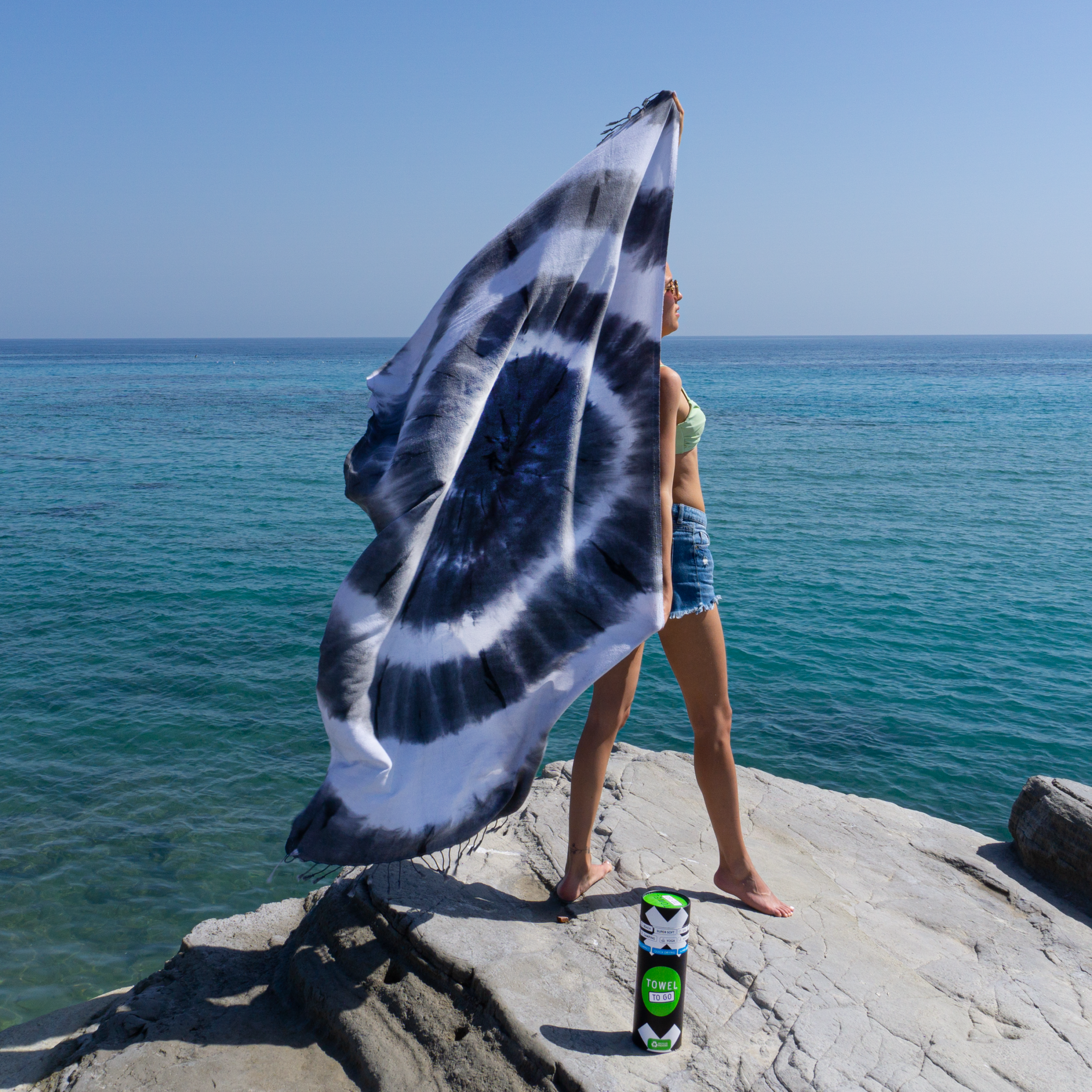 A vibrant tie-dye beach towel in black and white, elegantly displayed in a recycled gift box, showcasing its unique patterns and eco-friendly design.