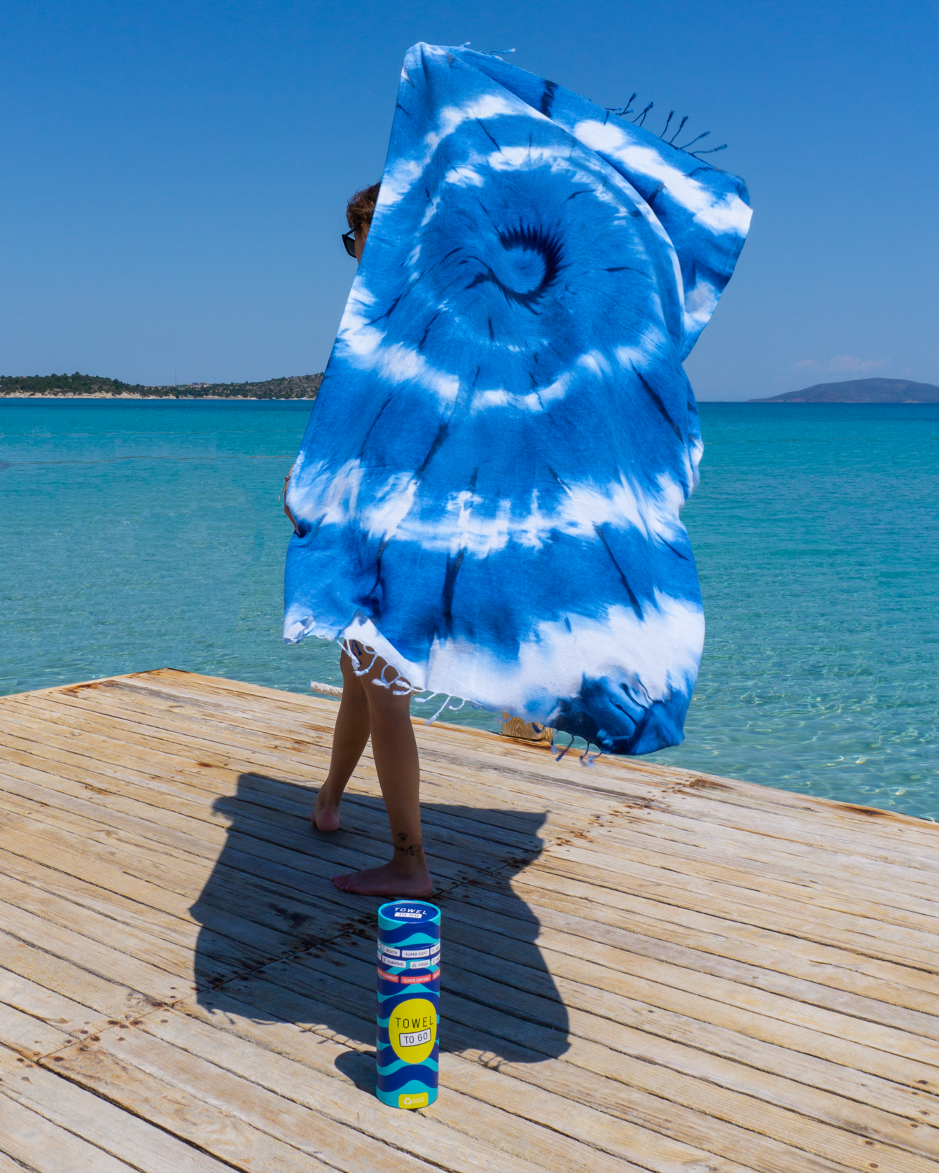 Vibrant blue and white tie-dye beach towel made from 100% cotton, rolled in a recycled gift box, showcasing unique patterns.