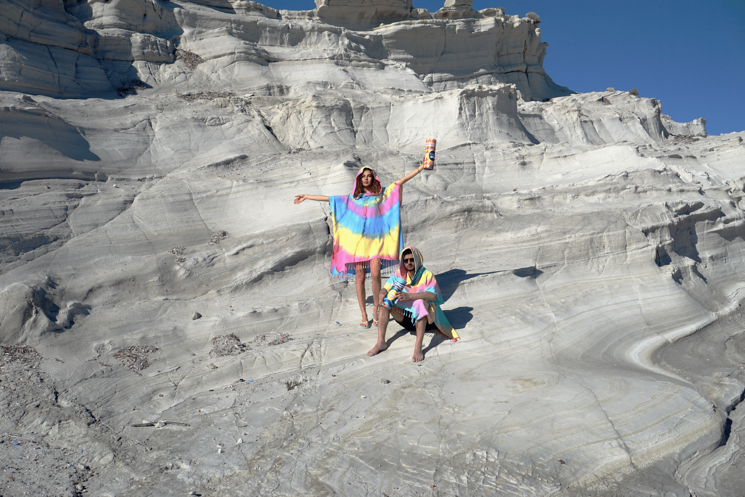 A stylish black and white tie dye hooded beach poncho displayed on a sandy beach, showcasing its unique patterns and relaxed fit.