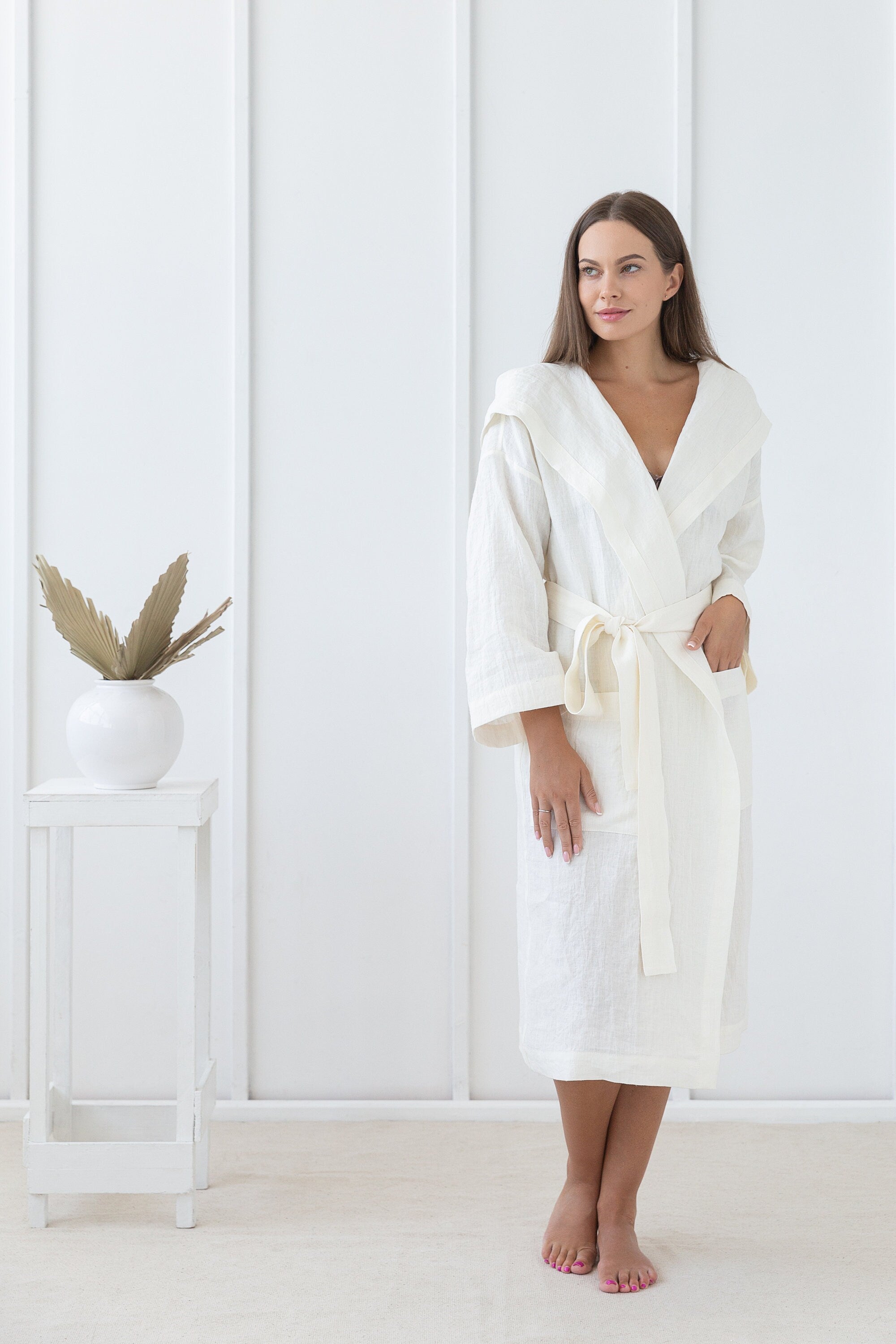 A cozy white linen robe with a wide hoodie, featuring two front pockets and a waist tie, made from 100% stonewashed European linen.