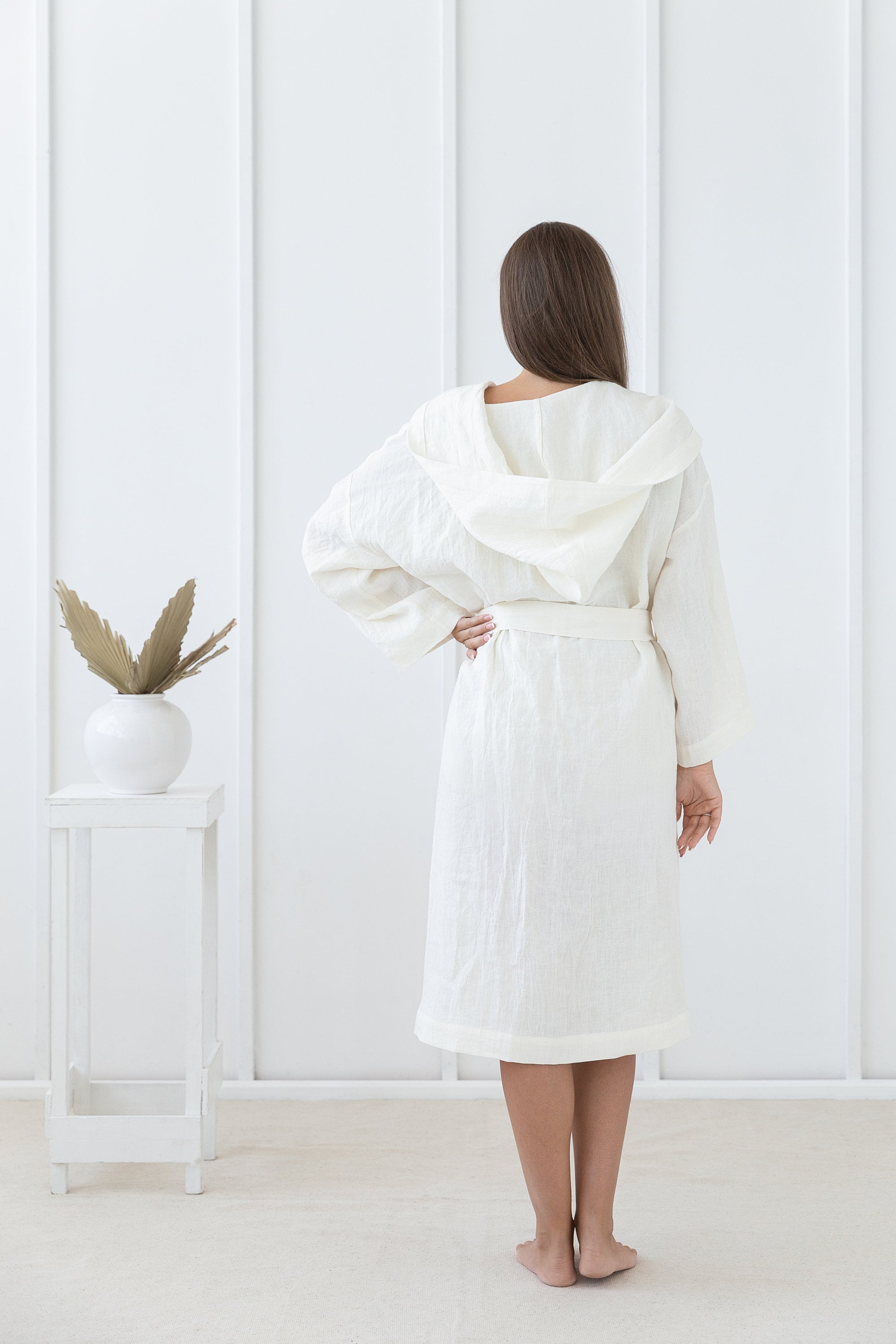 A cozy white linen robe with a wide hoodie, featuring two front pockets and a waist tie, made from 100% stonewashed European linen.