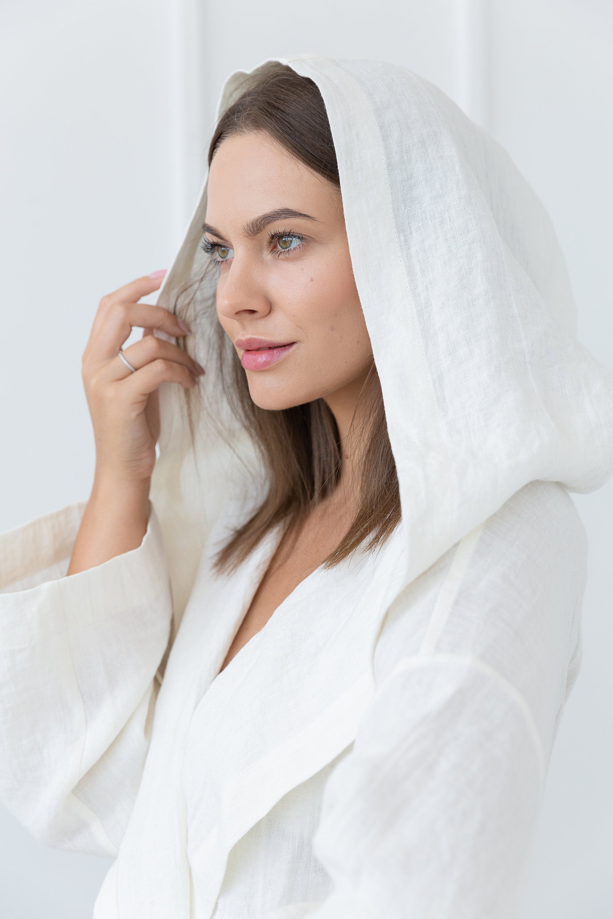 A cozy white linen robe with a wide hoodie, featuring two front pockets and a waist tie, made from 100% stonewashed European linen.