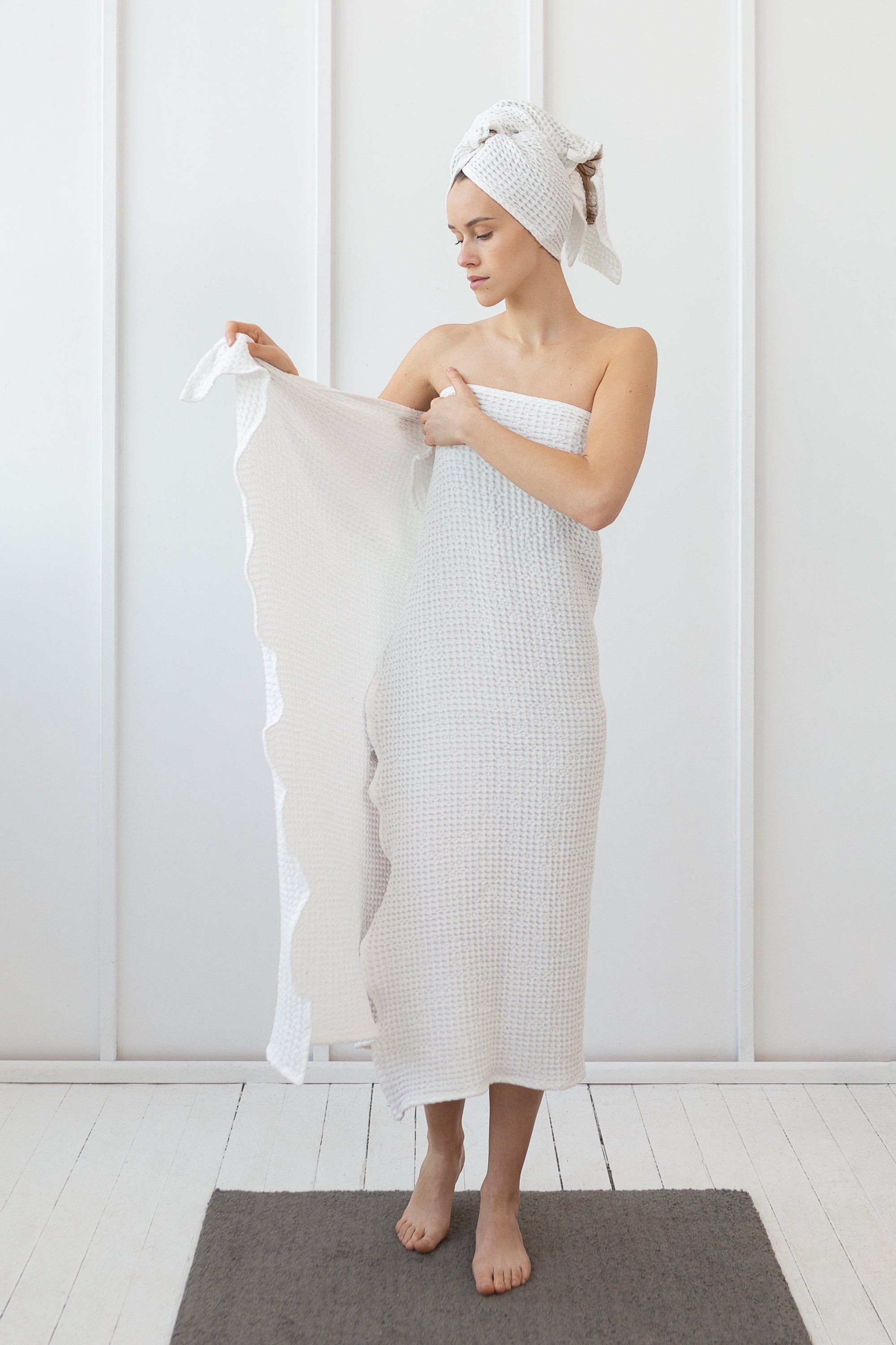 A set of white linen waffle towels featuring a stylish pattern, showcasing a hand towel and a bath towel, perfect for luxury drying.