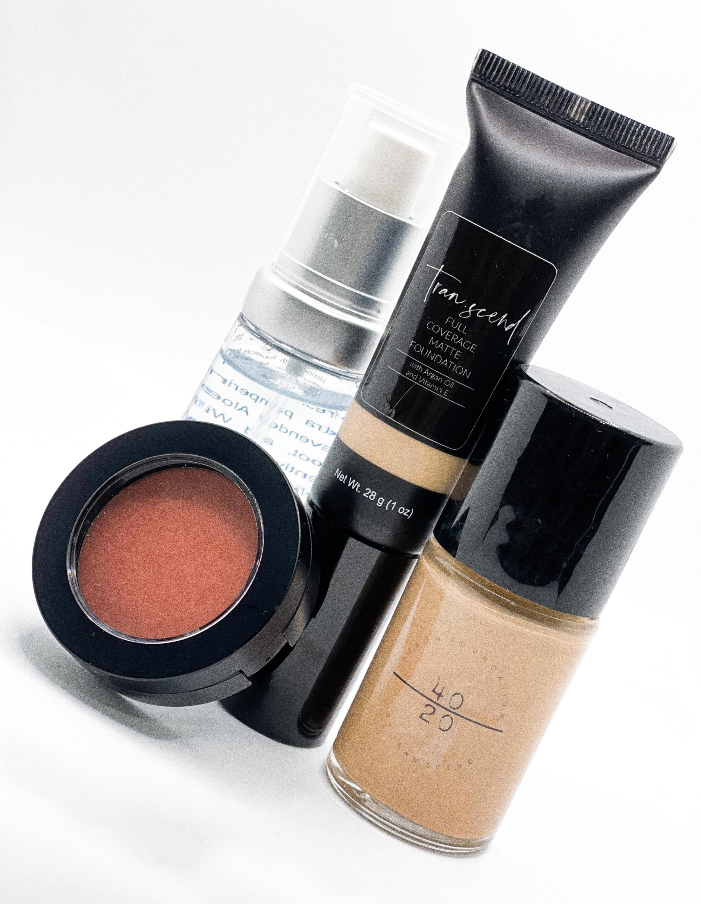 Ambitious Bundle featuring serum foundation, matte foundation, cream blusher, and setting spray arranged aesthetically.