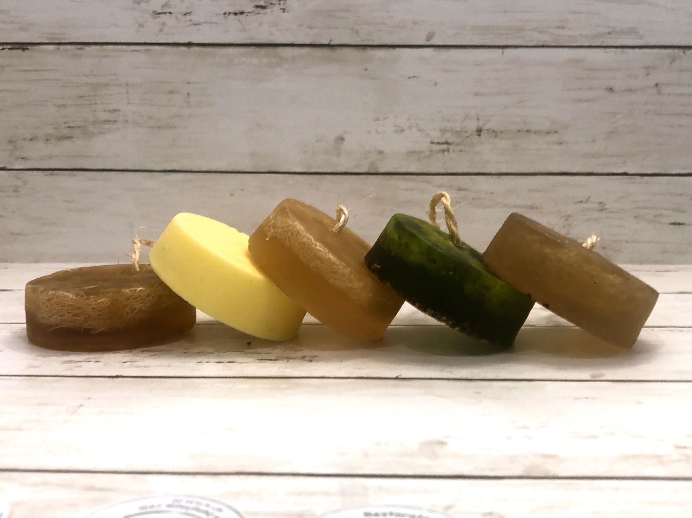 Artisanal Soap Collection featuring various natural soap bars with loofah and hanging cord, showcasing vibrant colors and textures.