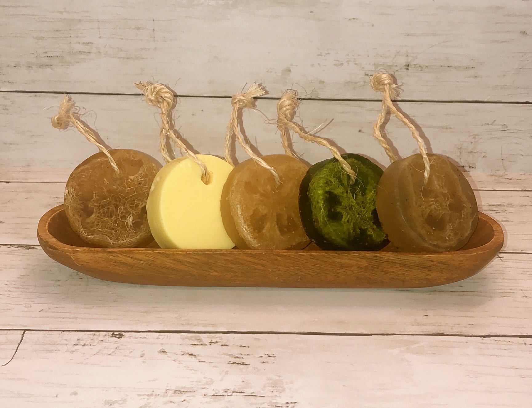 Artisanal Soap Collection featuring various natural soap bars with loofah and hanging cord, showcasing vibrant colors and textures.