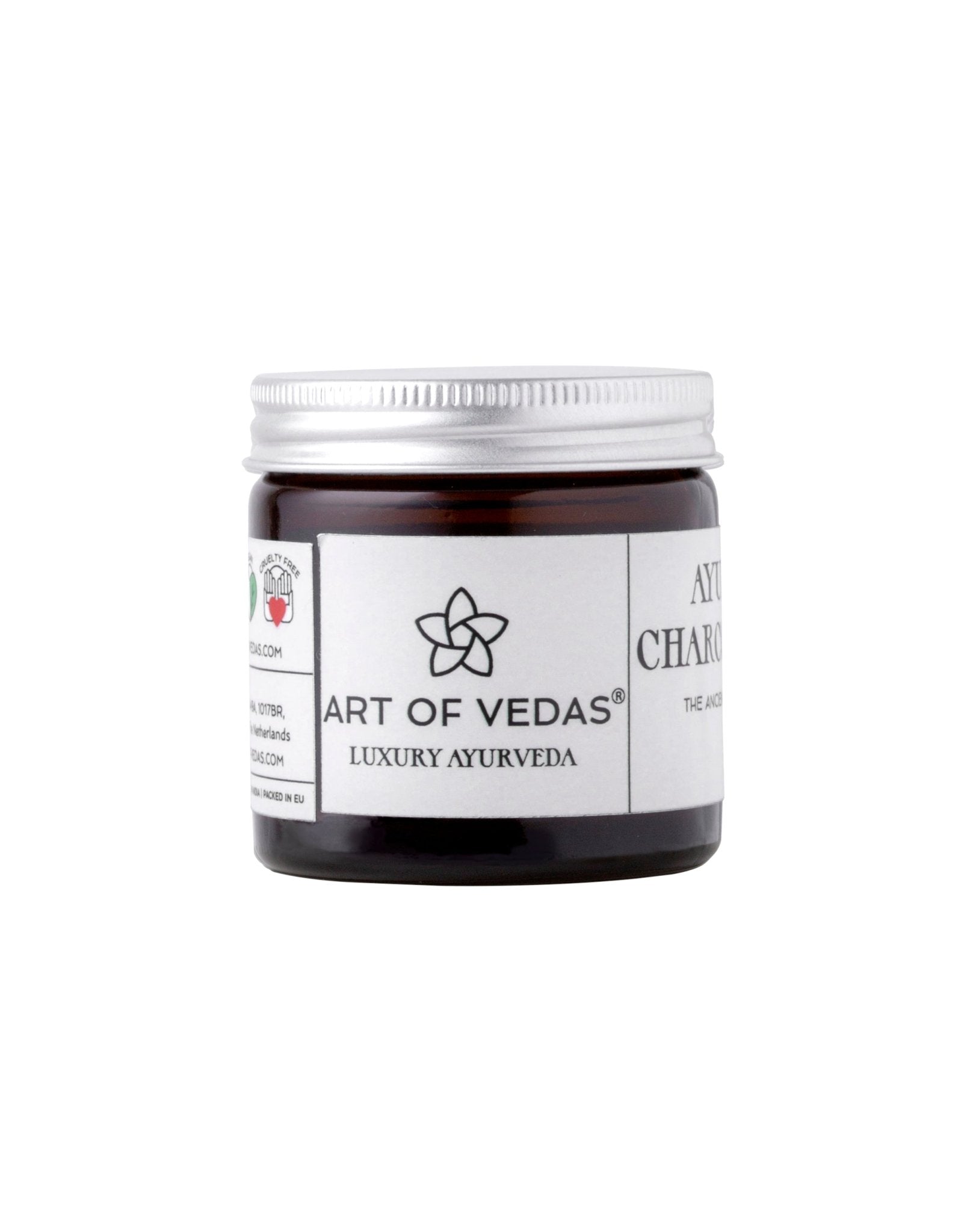 Ayurvedic Charcoal Scrub in a jar with natural ingredients around it, showcasing its organic and rejuvenating properties.