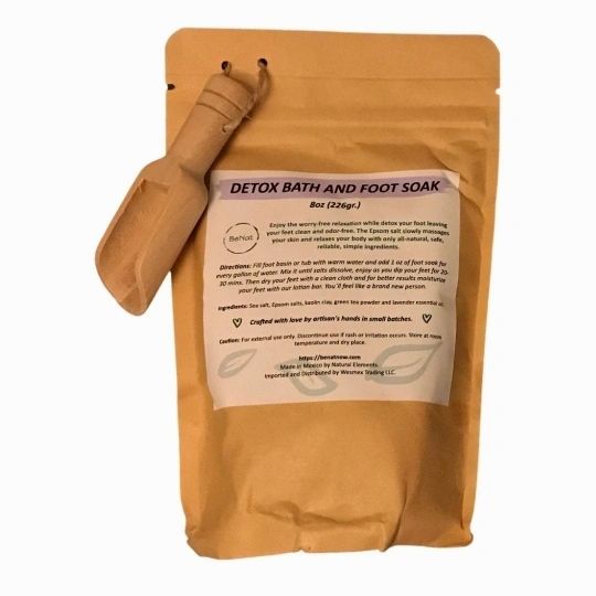 A beautifully packaged Bath and Foot Soak in a kraft bag with a mini bamboo scoop, showcasing natural ingredients like sea salts and lavender.