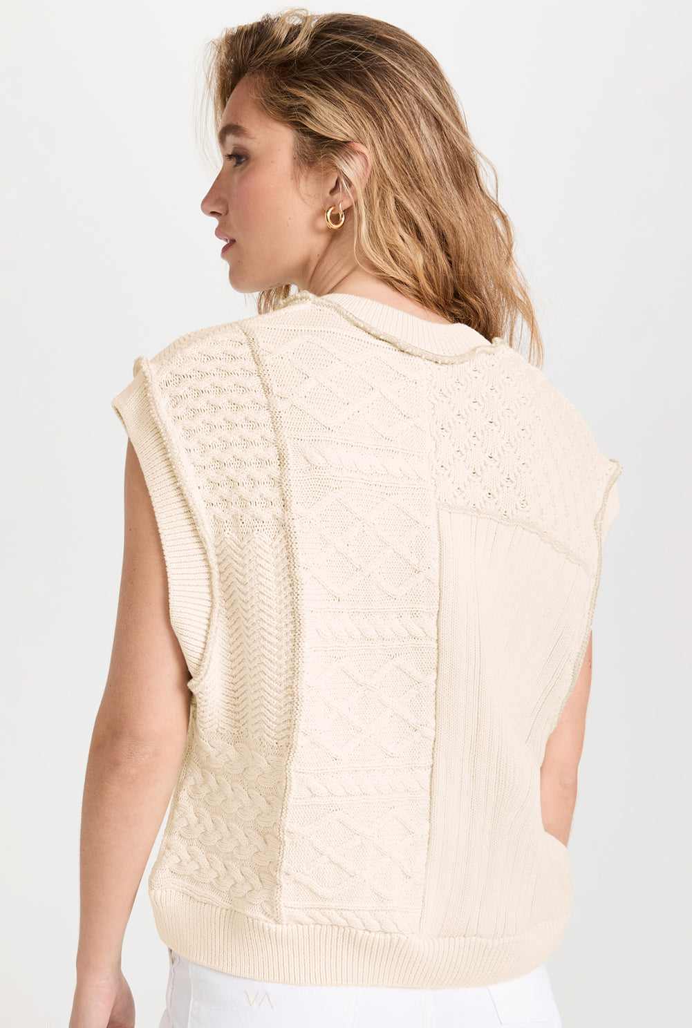 Beige cable knit sweater tank with dolman armholes, showcasing its soft texture and stylish design.