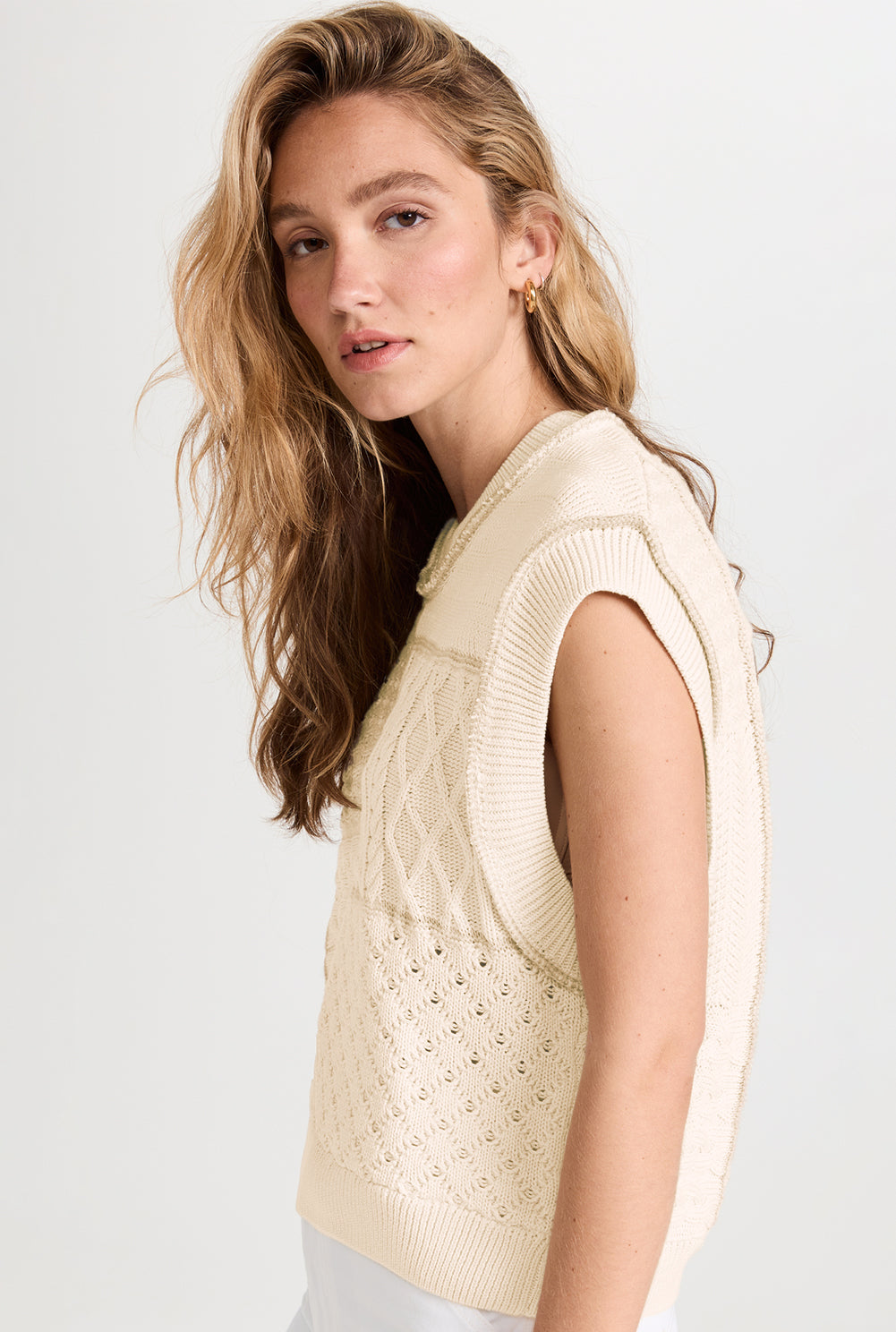 Beige cable knit sweater tank with dolman armholes, showcasing its soft texture and stylish design.