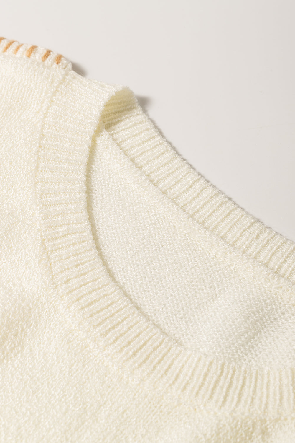 Beige sweater featuring exposed stitching, drop shoulder design, and a chest pocket, styled on a mannequin.