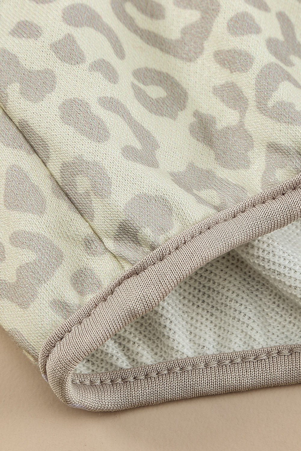 Beige lapel sweatshirt with leopard print, featuring a snap front and kangaroo pocket, perfect for casual wear.