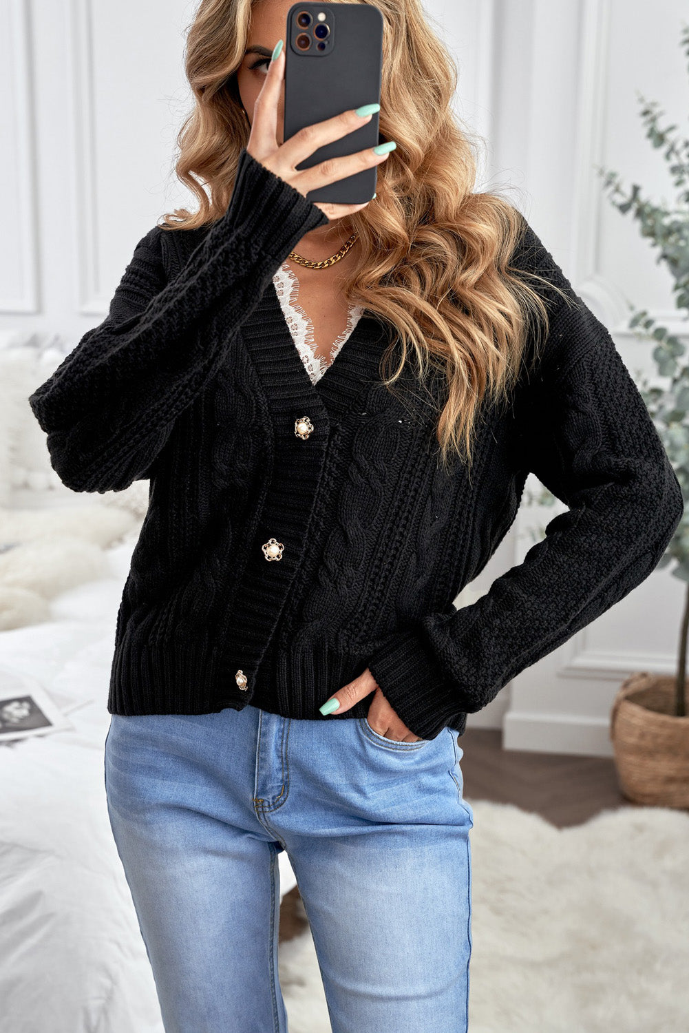 A stylish black knit cardigan featuring button closures, deep v-neck, and long drop-shoulder sleeves, perfect for layering in cold weather.