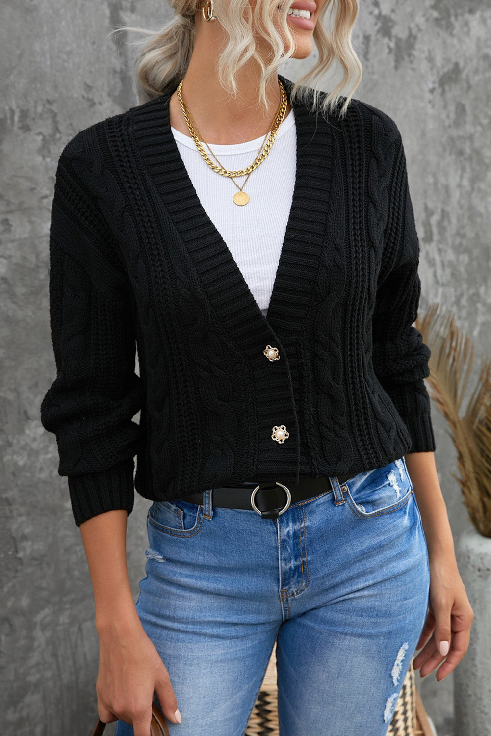 A stylish black knit cardigan featuring button closures, deep v-neck, and long drop-shoulder sleeves, perfect for layering in cold weather.