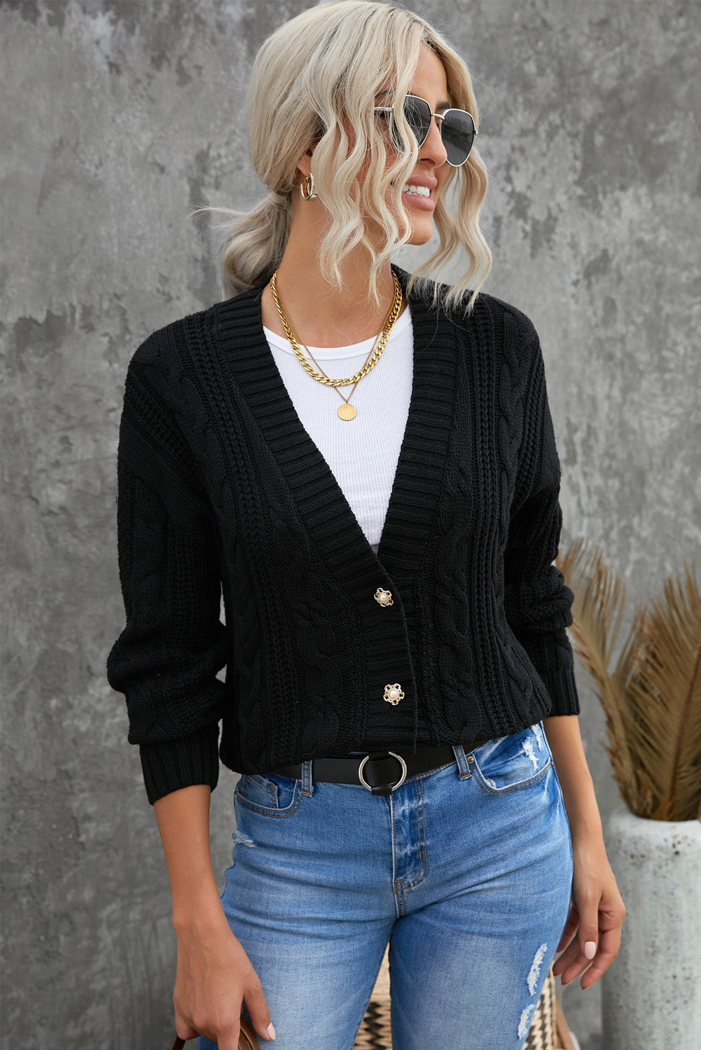 A stylish black knit cardigan featuring button closures, deep v-neck, and long drop-shoulder sleeves, perfect for layering in cold weather.