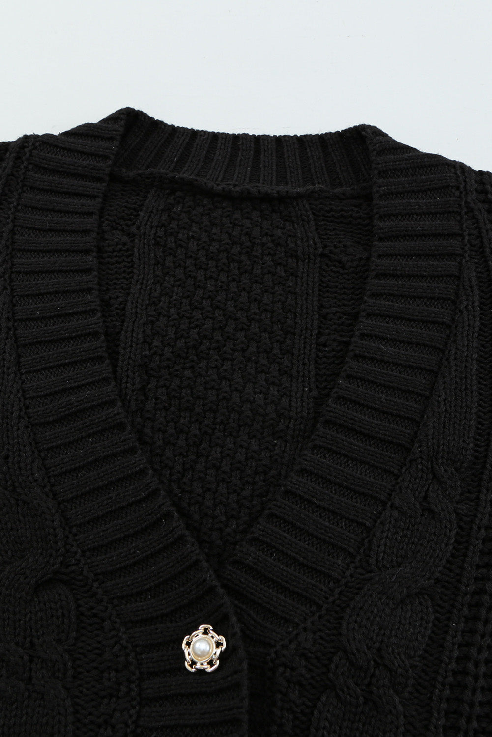 A stylish black knit cardigan featuring button closures, deep v-neck, and long drop-shoulder sleeves, perfect for layering in cold weather.