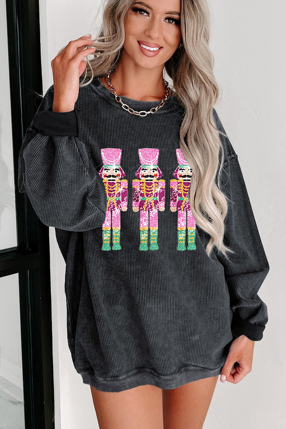 Black Christmas sweatshirt featuring sequined nutcracker design with a mineral wash finish, perfect for holiday celebrations.