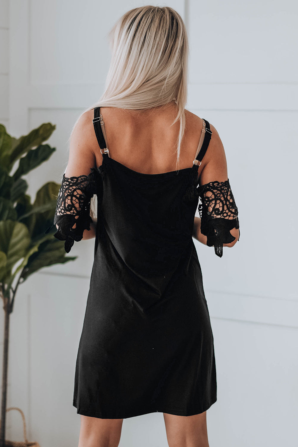 A stylish black mini dress featuring cold shoulder design, V-neckline, and lace sleeves, perfect for a chic and sexy look.