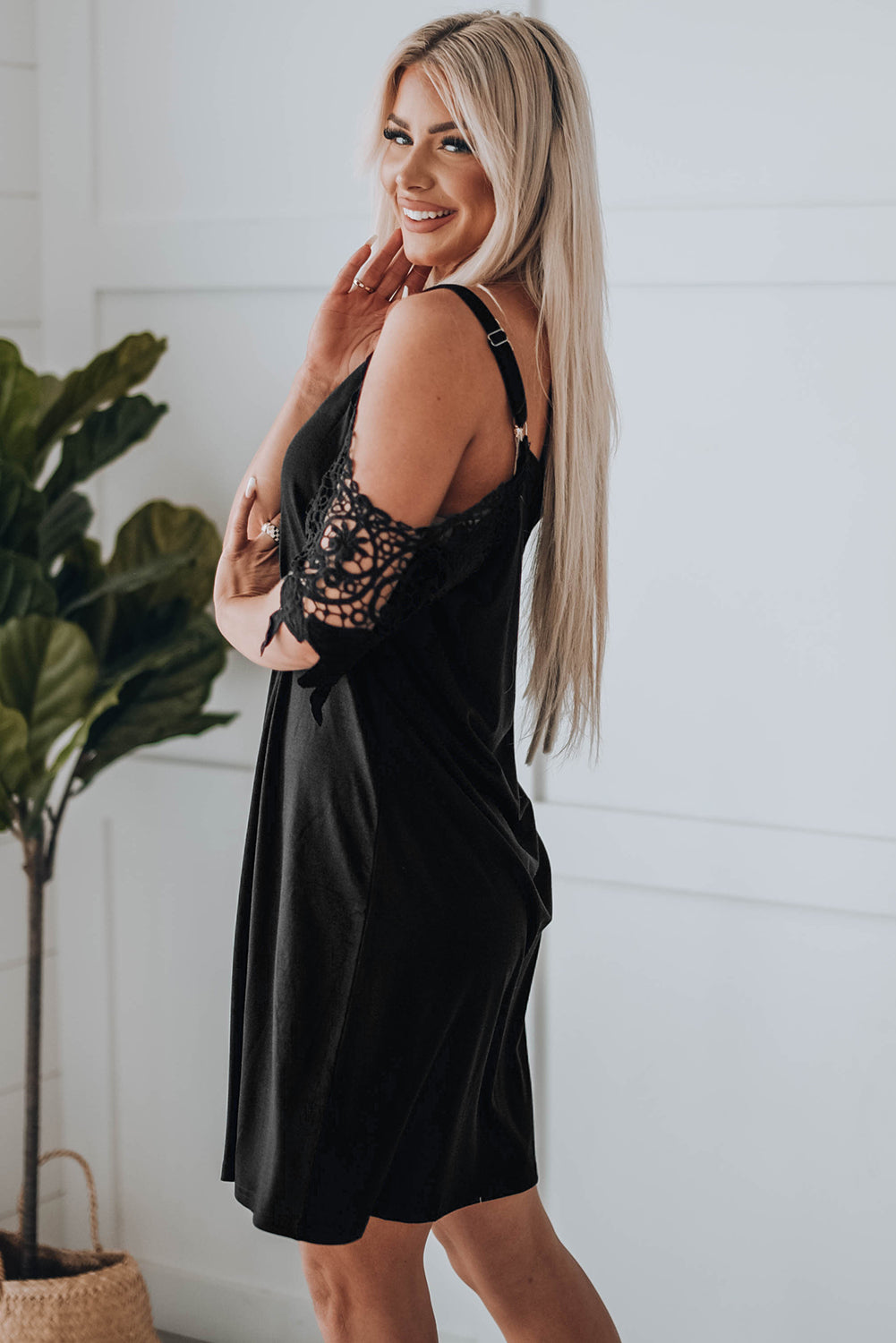 A stylish black mini dress featuring cold shoulder design, V-neckline, and lace sleeves, perfect for a chic and sexy look.