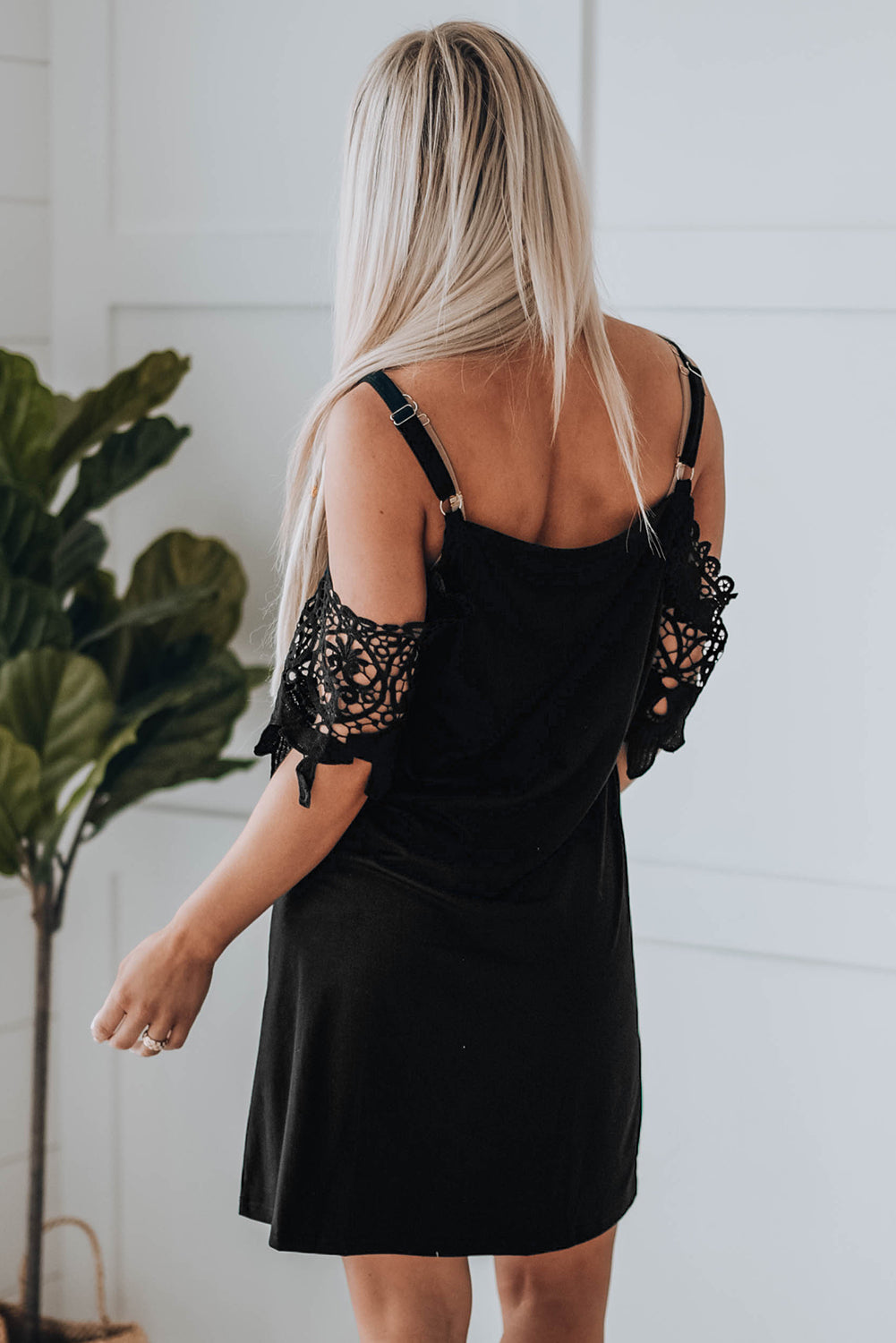 A stylish black mini dress featuring cold shoulder design, V-neckline, and lace sleeves, perfect for a chic and sexy look.