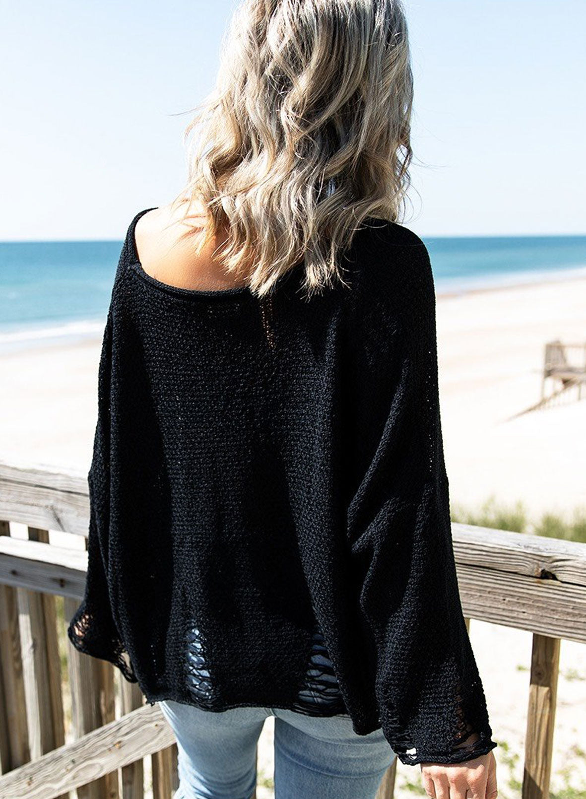 Black distressed boxy fit crop knit sweater with long sleeves, showcasing a relaxed style and trendy details.