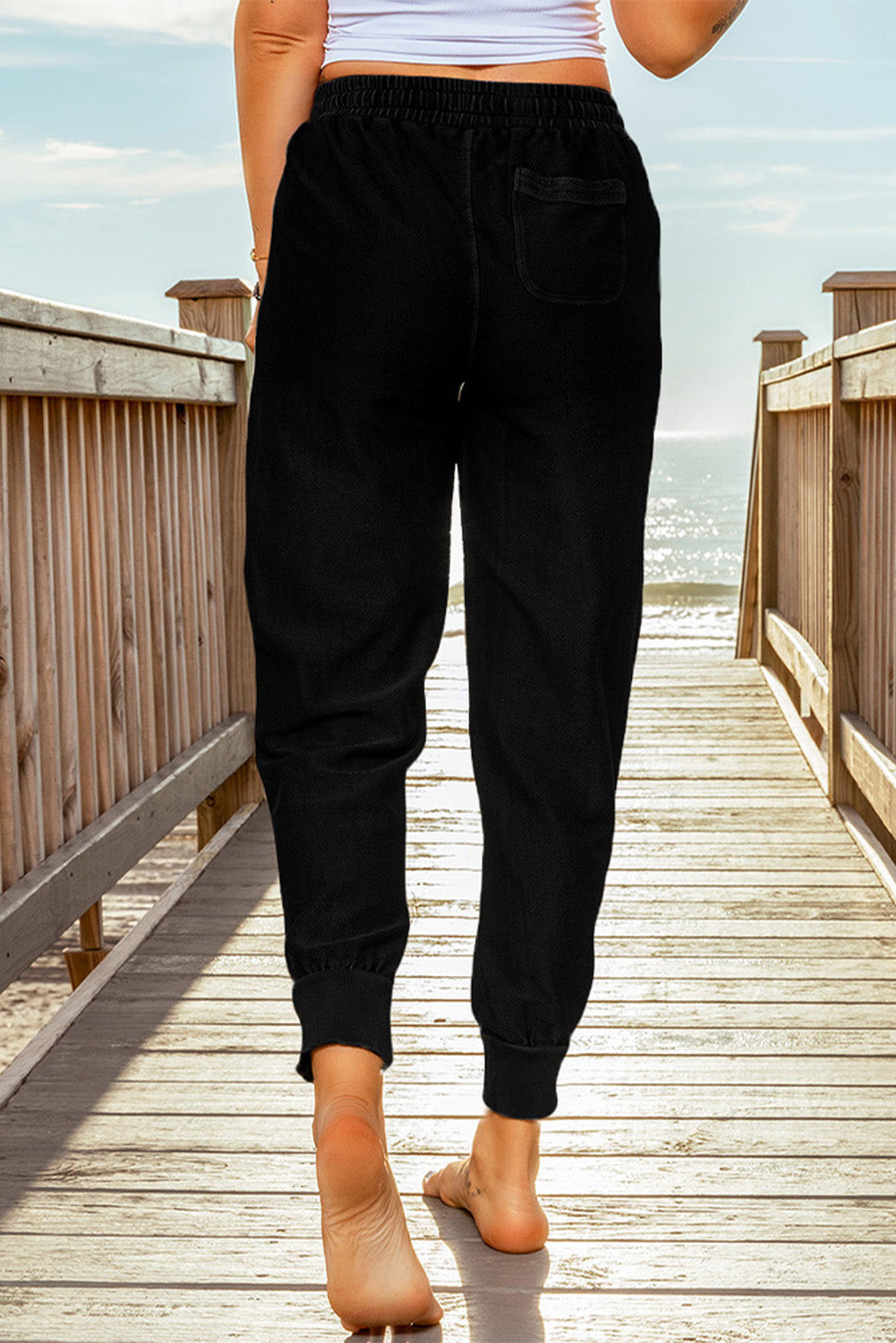 Black elastic waist jogger pants with side pockets, showcasing a relaxed fit and drawstring waist, perfect for casual wear.