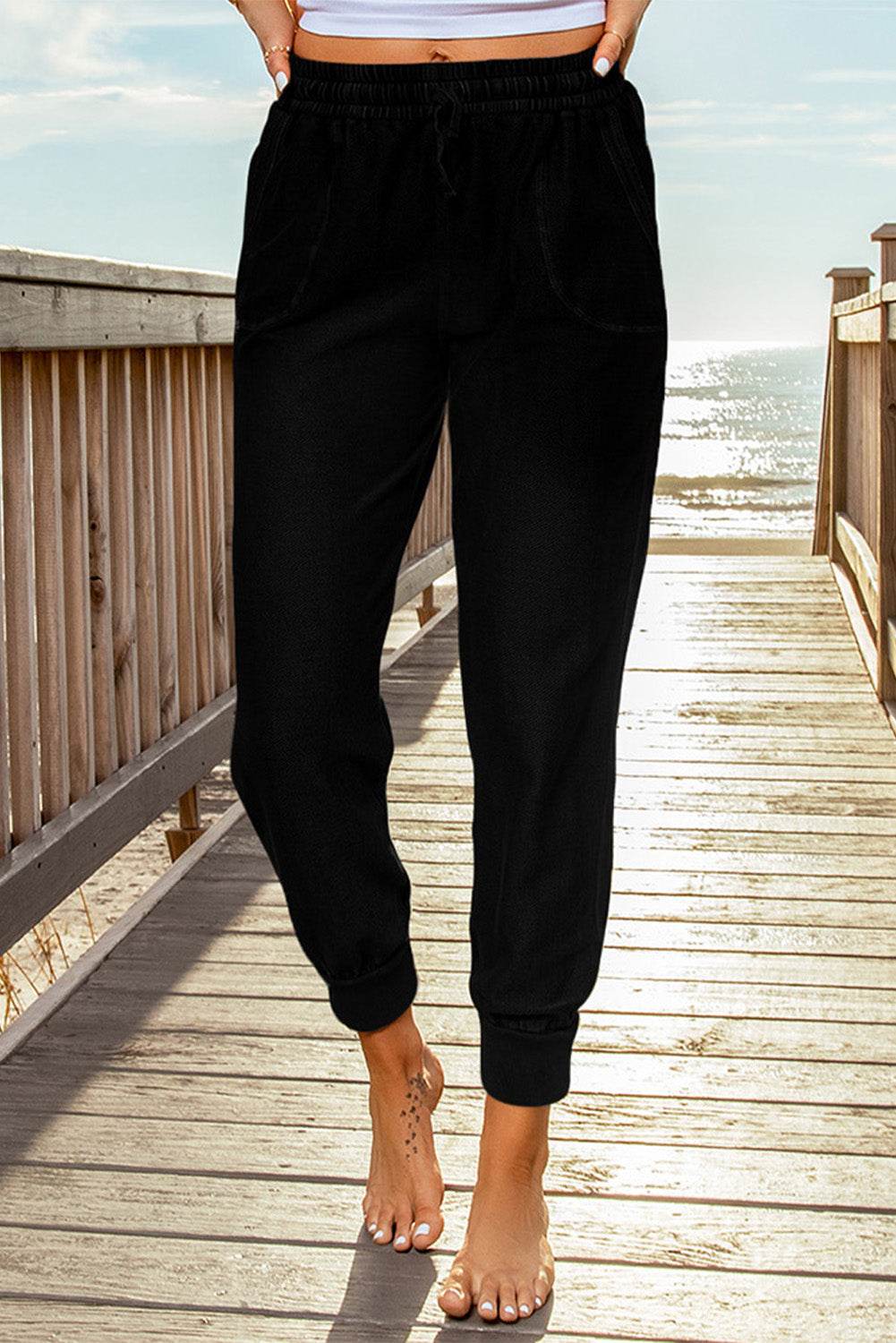 Black elastic waist jogger pants with side pockets, showcasing a relaxed fit and drawstring waist, perfect for casual wear.